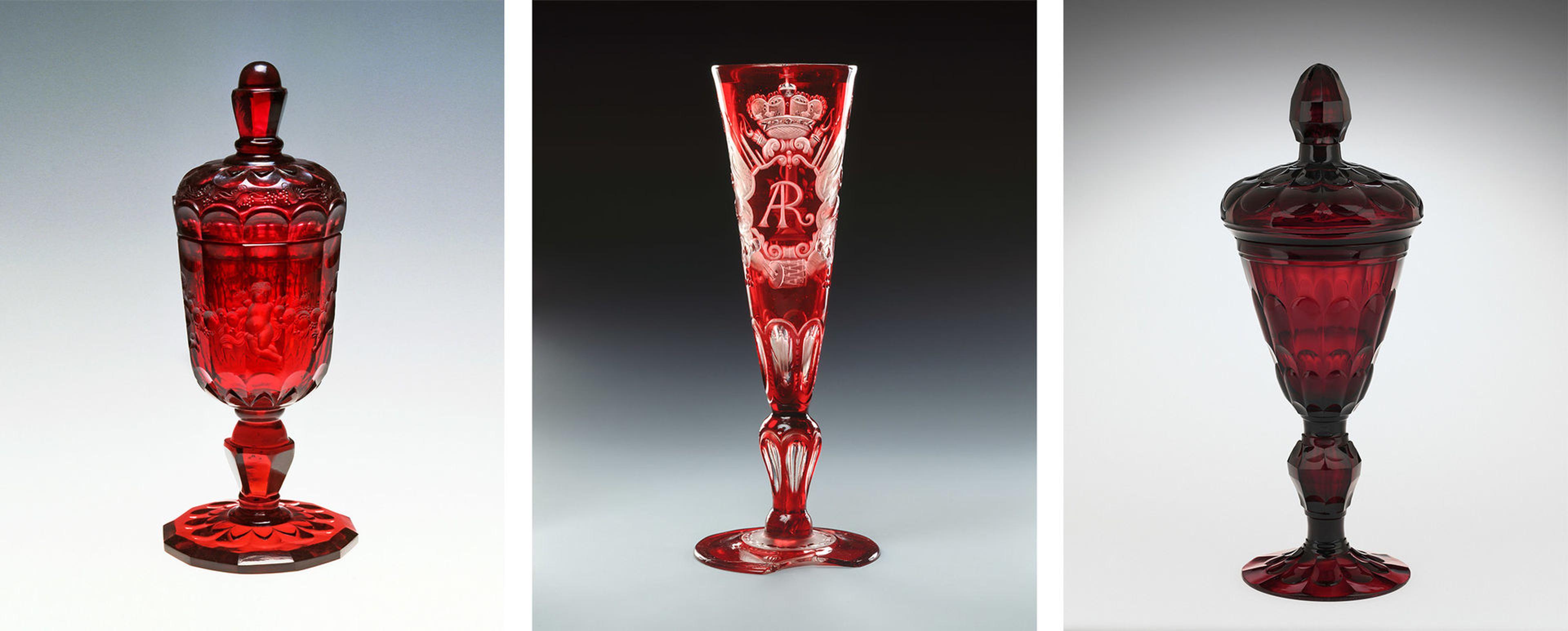 A composite of three ruby-red goblets, two with lids and the third intricately engraved with the initials "AR"