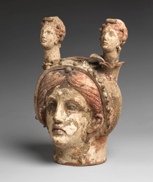 Hellenistic terracotta vase in the form of a woman's face, topped with two smaller, long-necked female heads