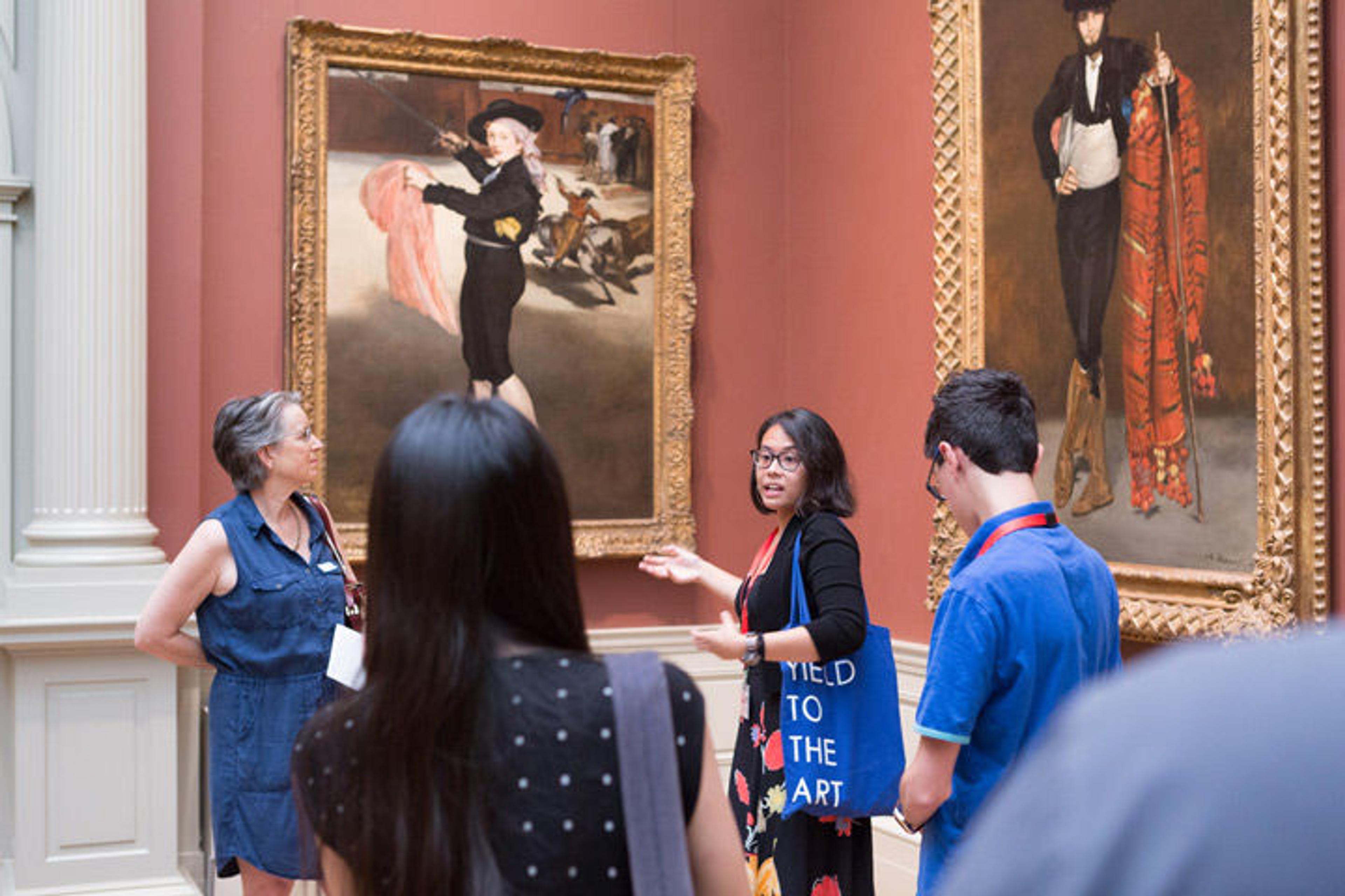 An educator talks with a group of college-age students about a Manet work in the European Paintings galleries