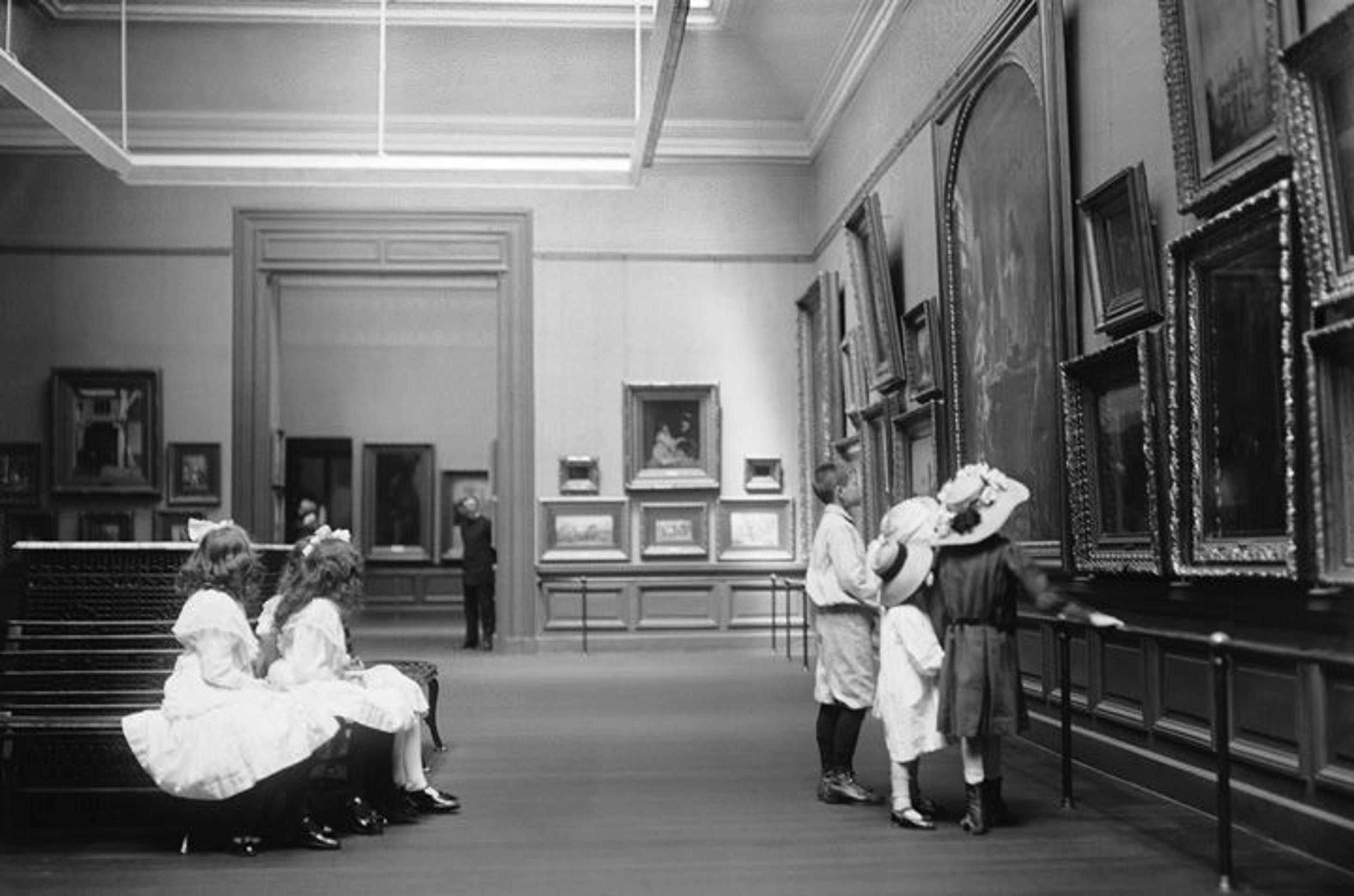 A group of children look at paintings in a gallery in 1910