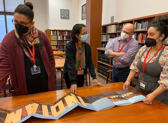 4 people around a table discussing an artists' book