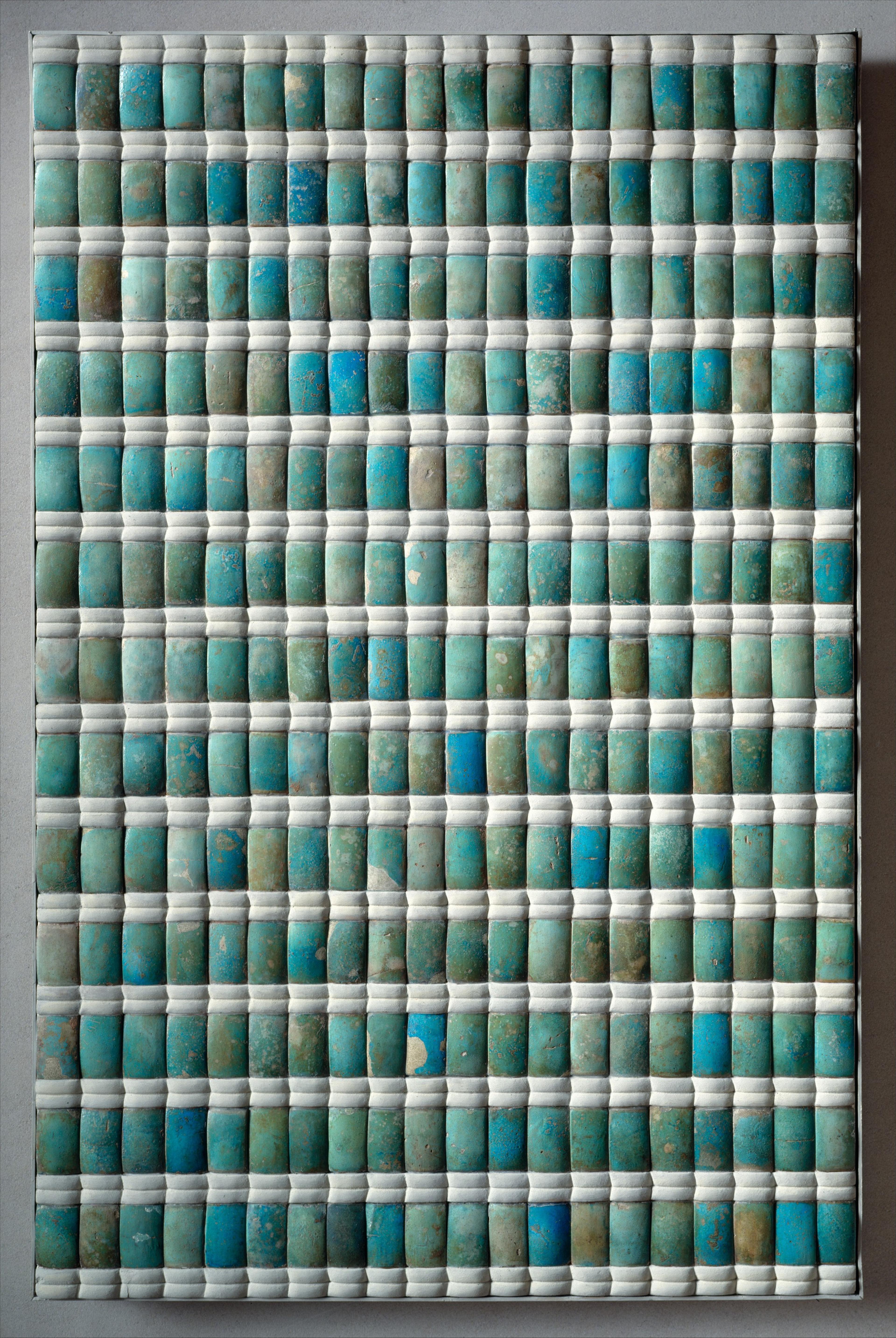 Alternating rows of blue and white faience titles. The blue tiles are tall and thin and the white titles are short with a line through the middle.