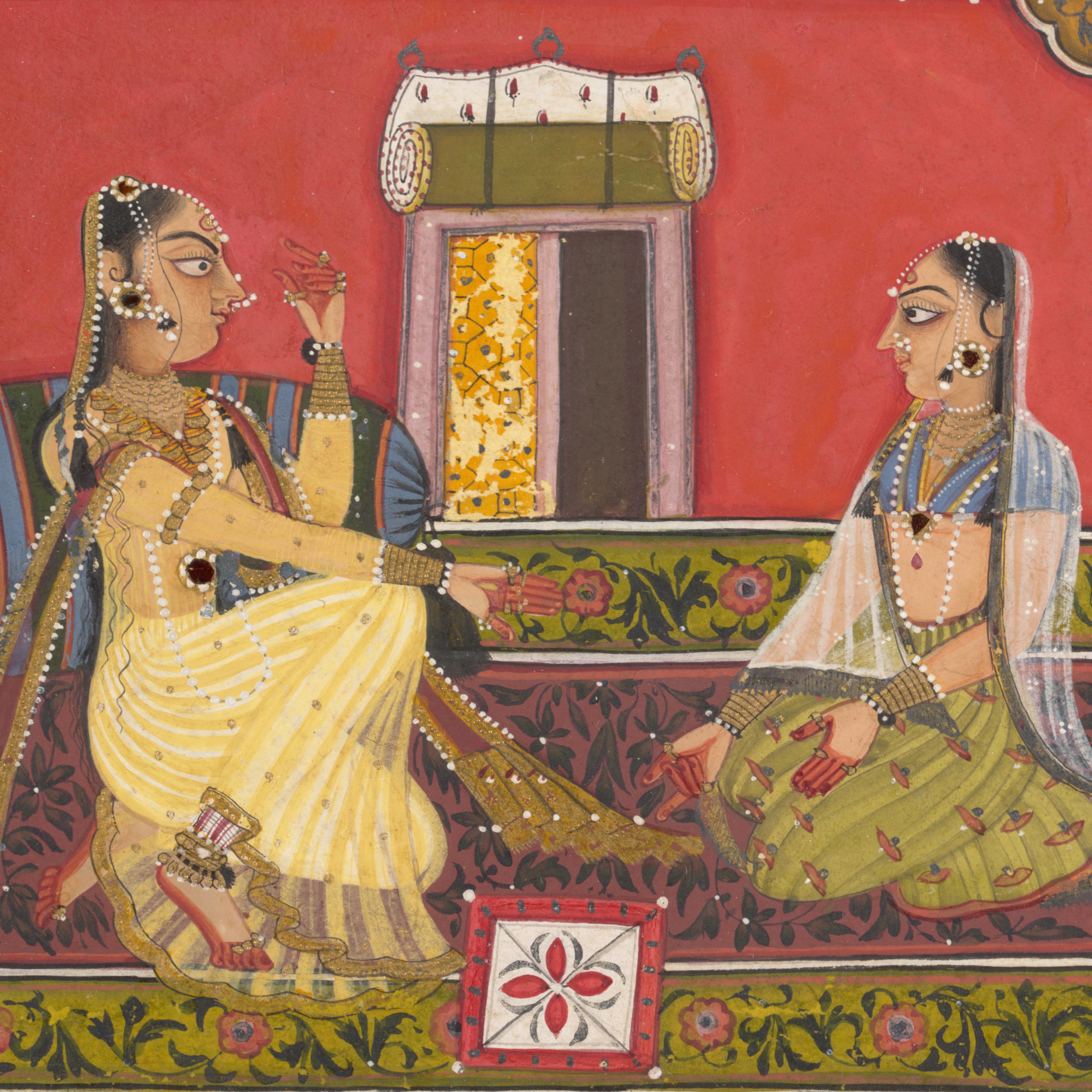 Two women in opulent dress and jewelry sit facing each other on a patterned carpet