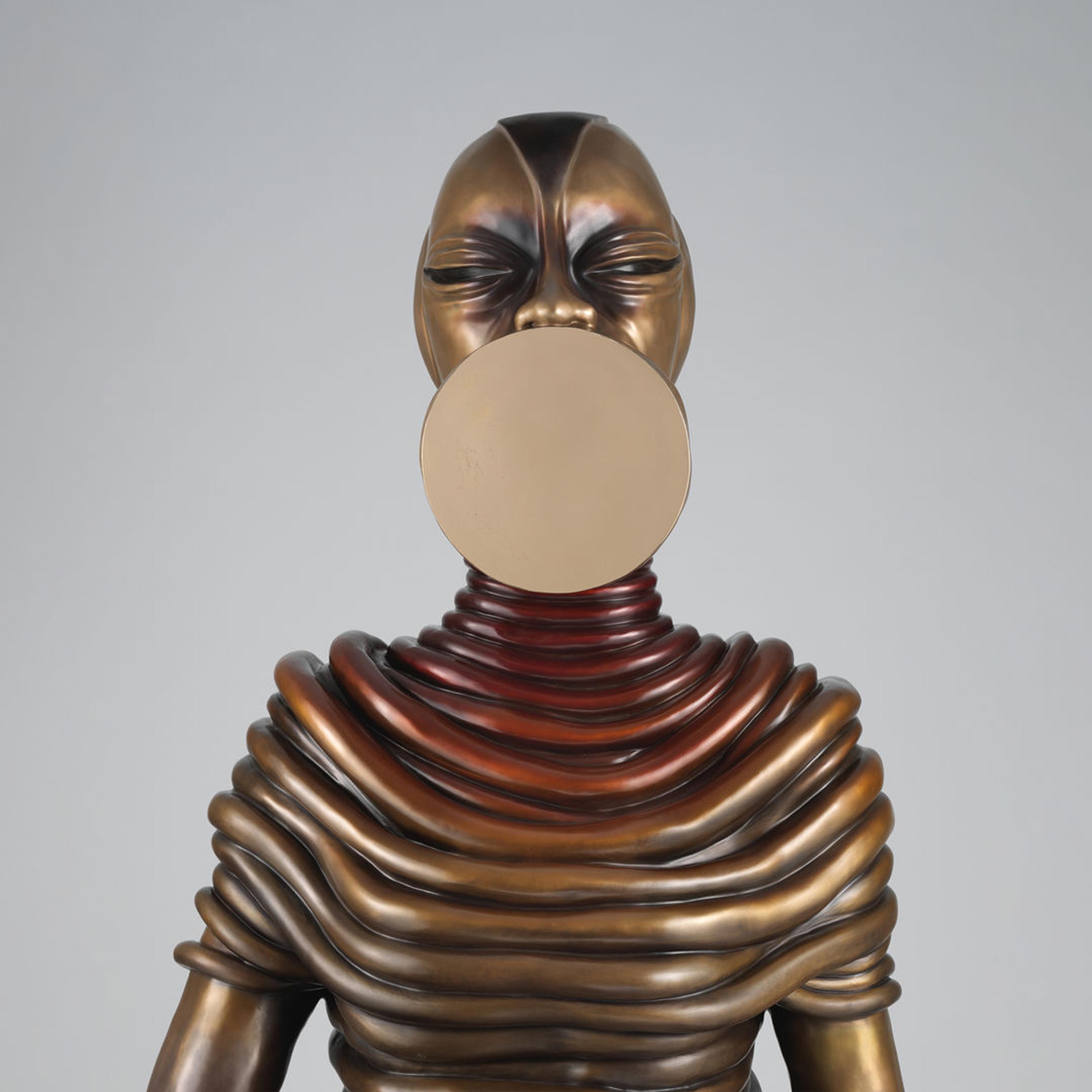 Detail of Wangechi Mutu’s bronze sculpture of a seated female figure; the entire figure is decorated in draped coils and the mouth is shaped like a flat polished disk.