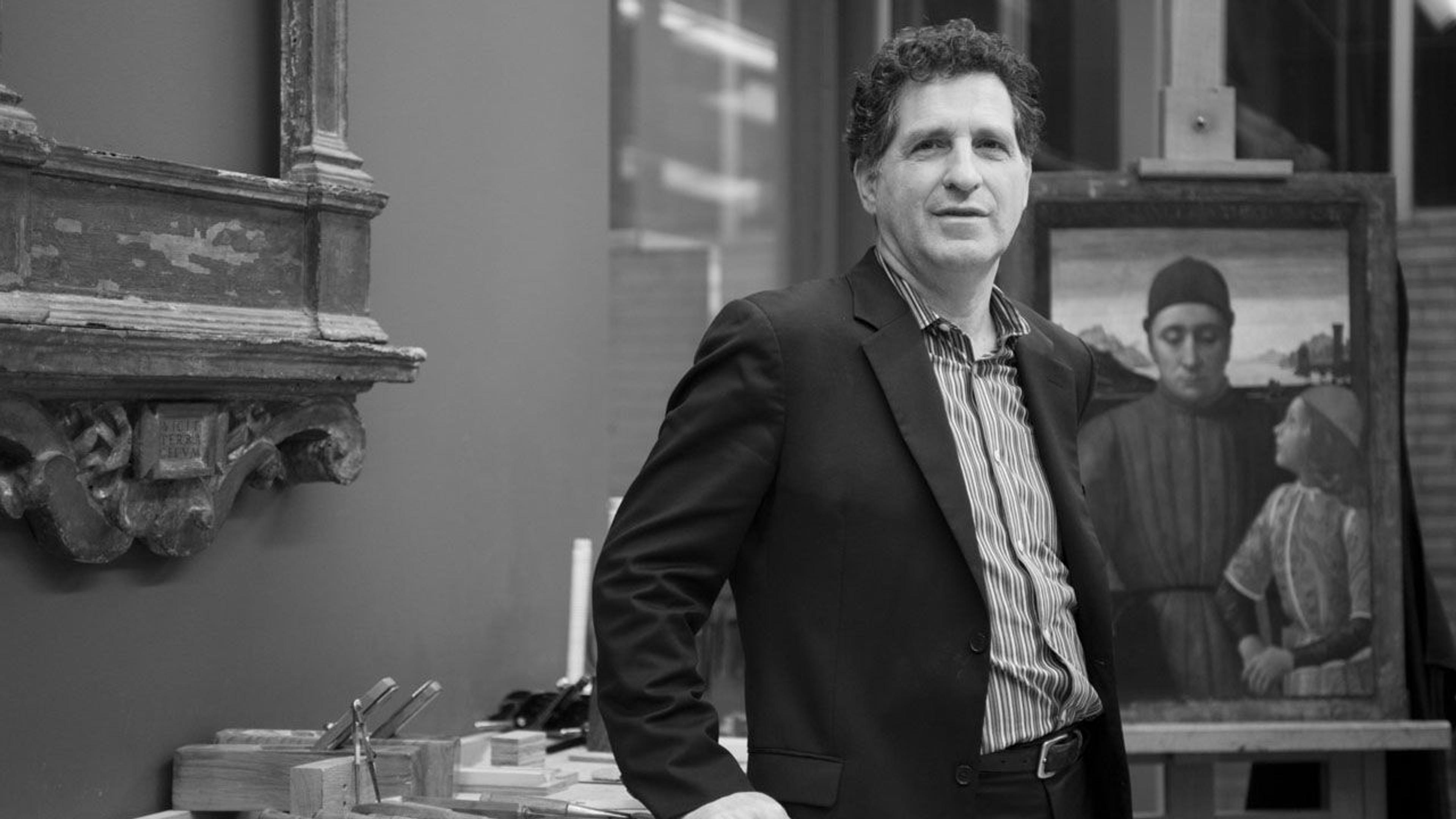 Black and white photograph of paintings conservator George Bisacca standing in front of a painting at The Met