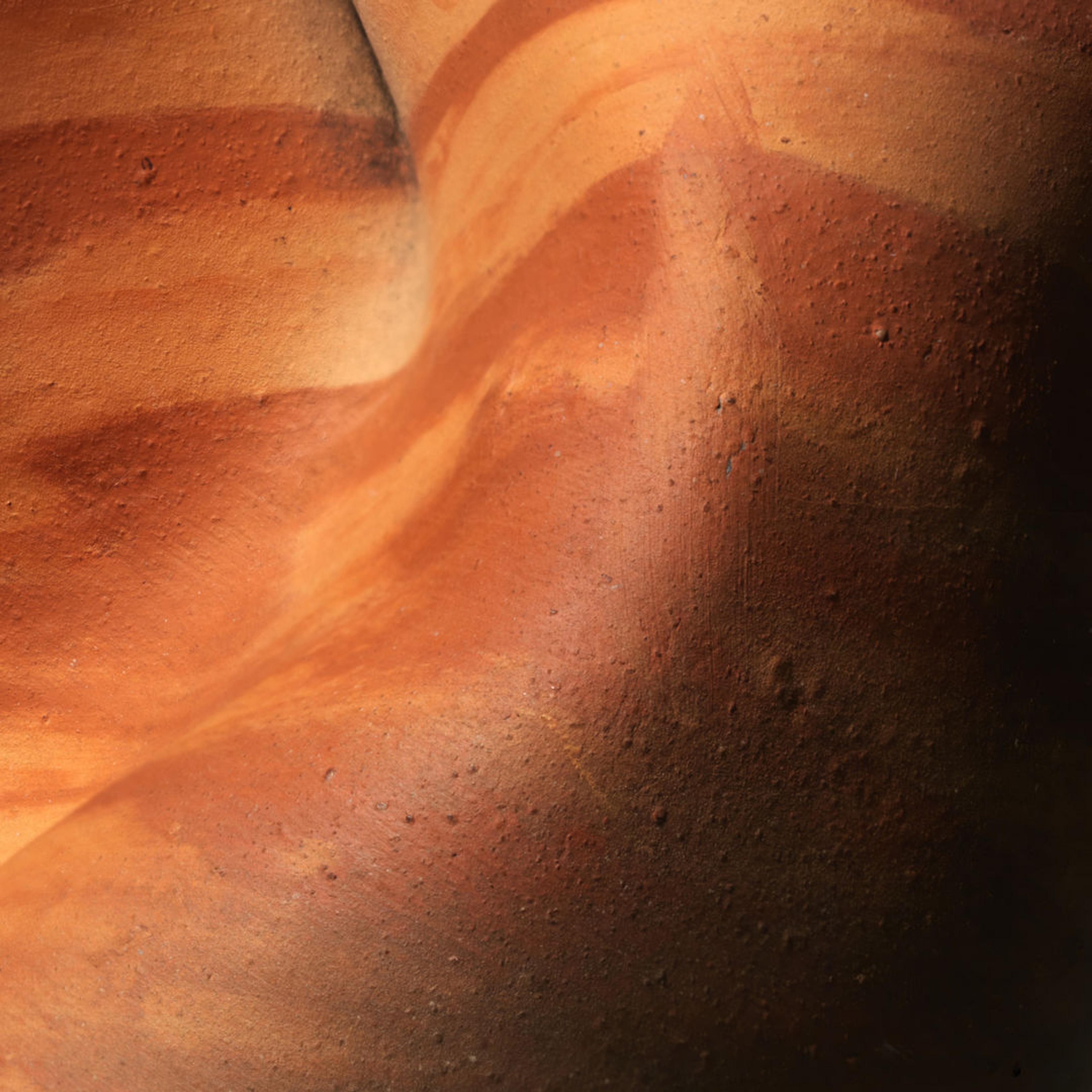 Detail of the curves of a clay vessel with stripes of dark and light red clay
