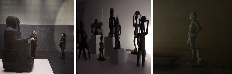 Left: two people stand in a dark gallery with a large statue of a seated figure to their left. Center: tall, thin statues arranged in a tableau cast shadows as they are hit by a flashlight beam. Right: a statue of a standing man is cast in darkness.