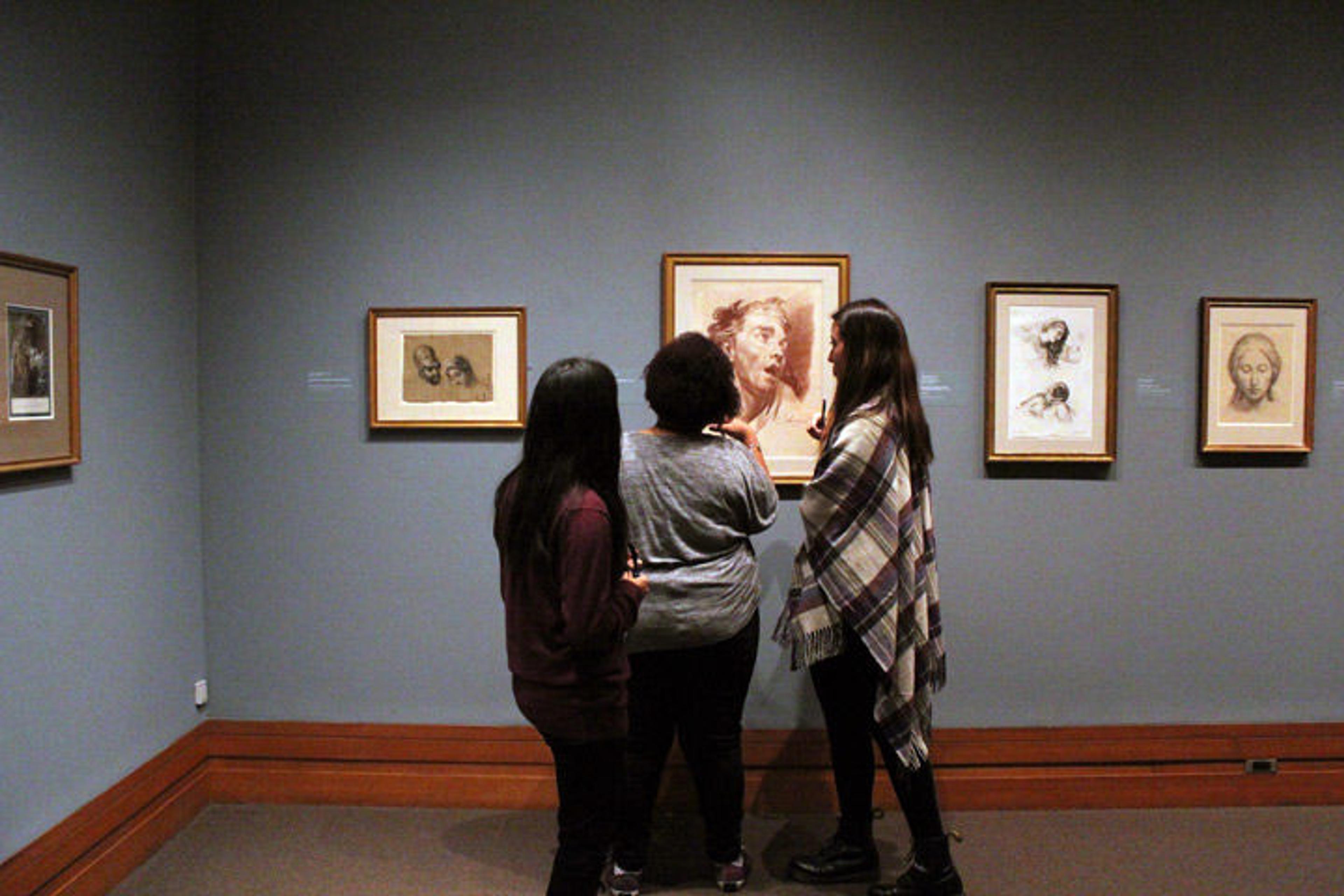 Three interns in the galleries discussing a print