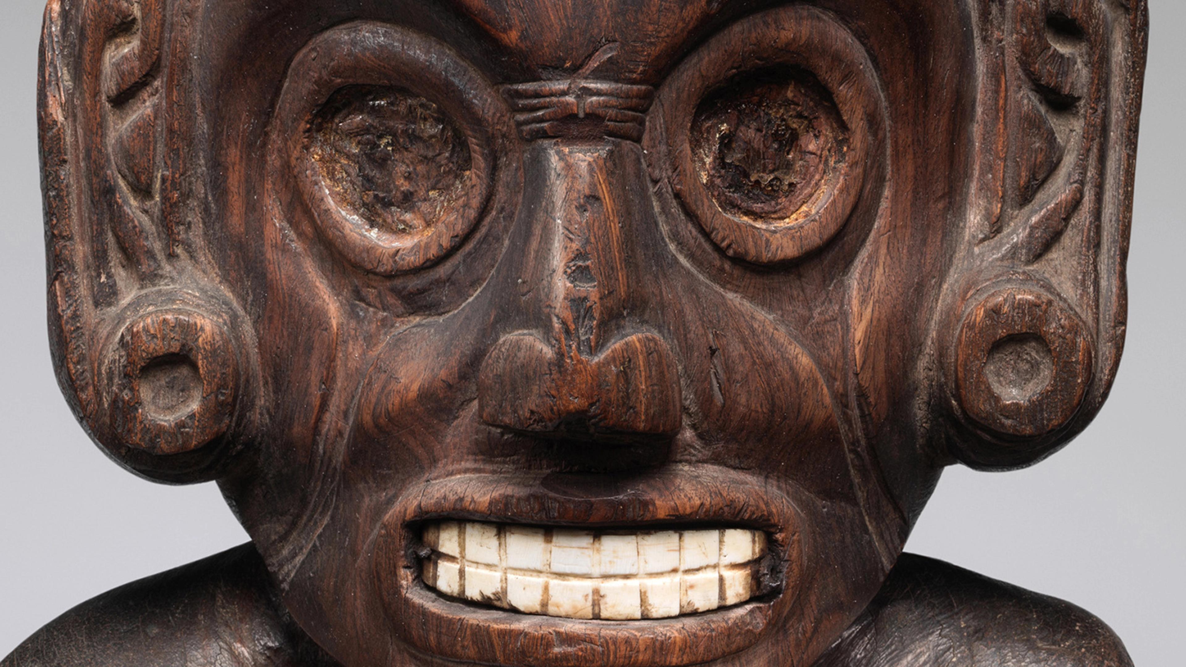 Close-up of the Met's wooden Zemí figure, which depicts a carved face with white shell for teeth.