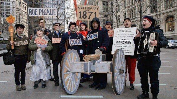 A video still of a group of protesters on the street holding signs in French