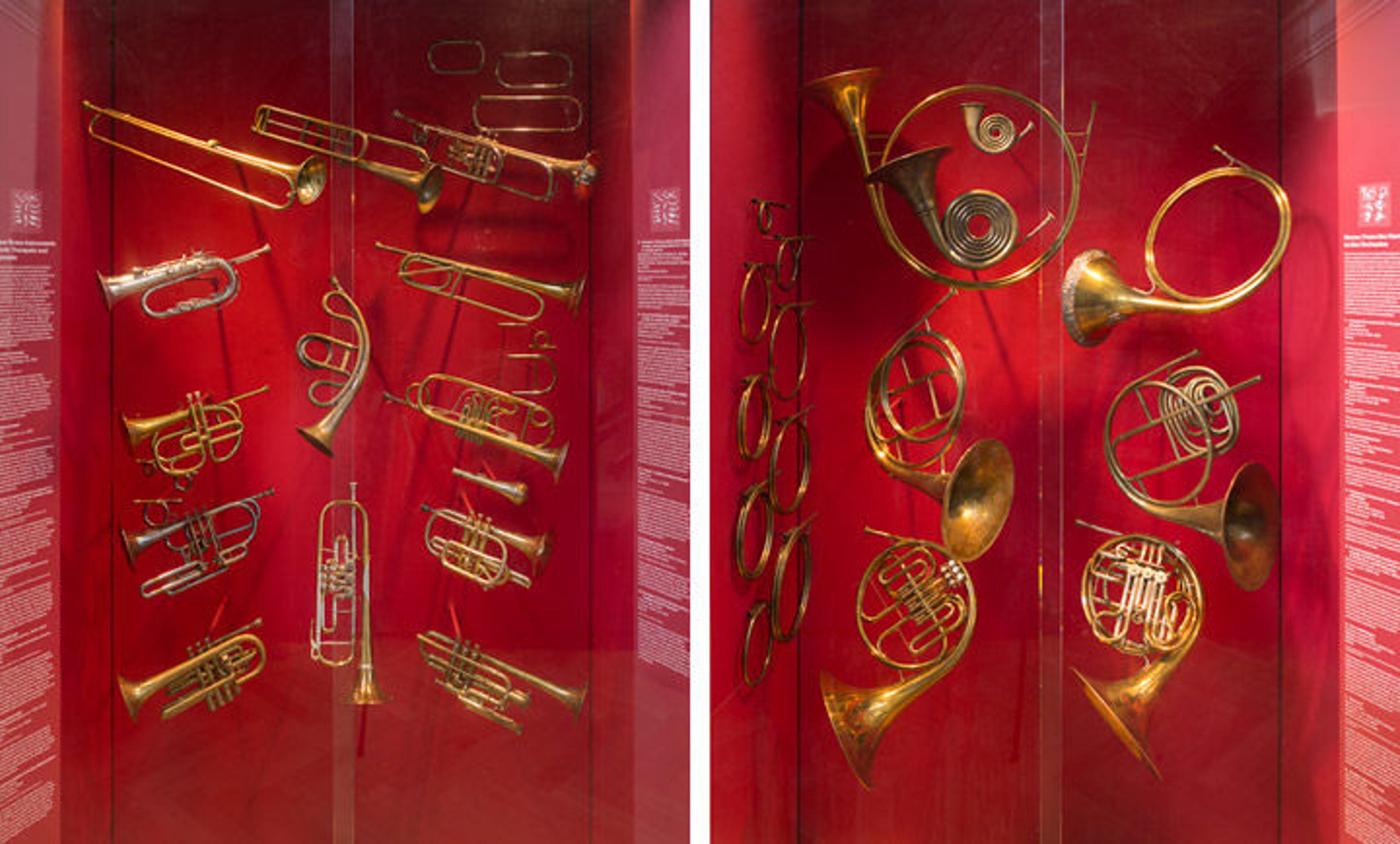 Views of two wall cases showing various trumpets and French horns