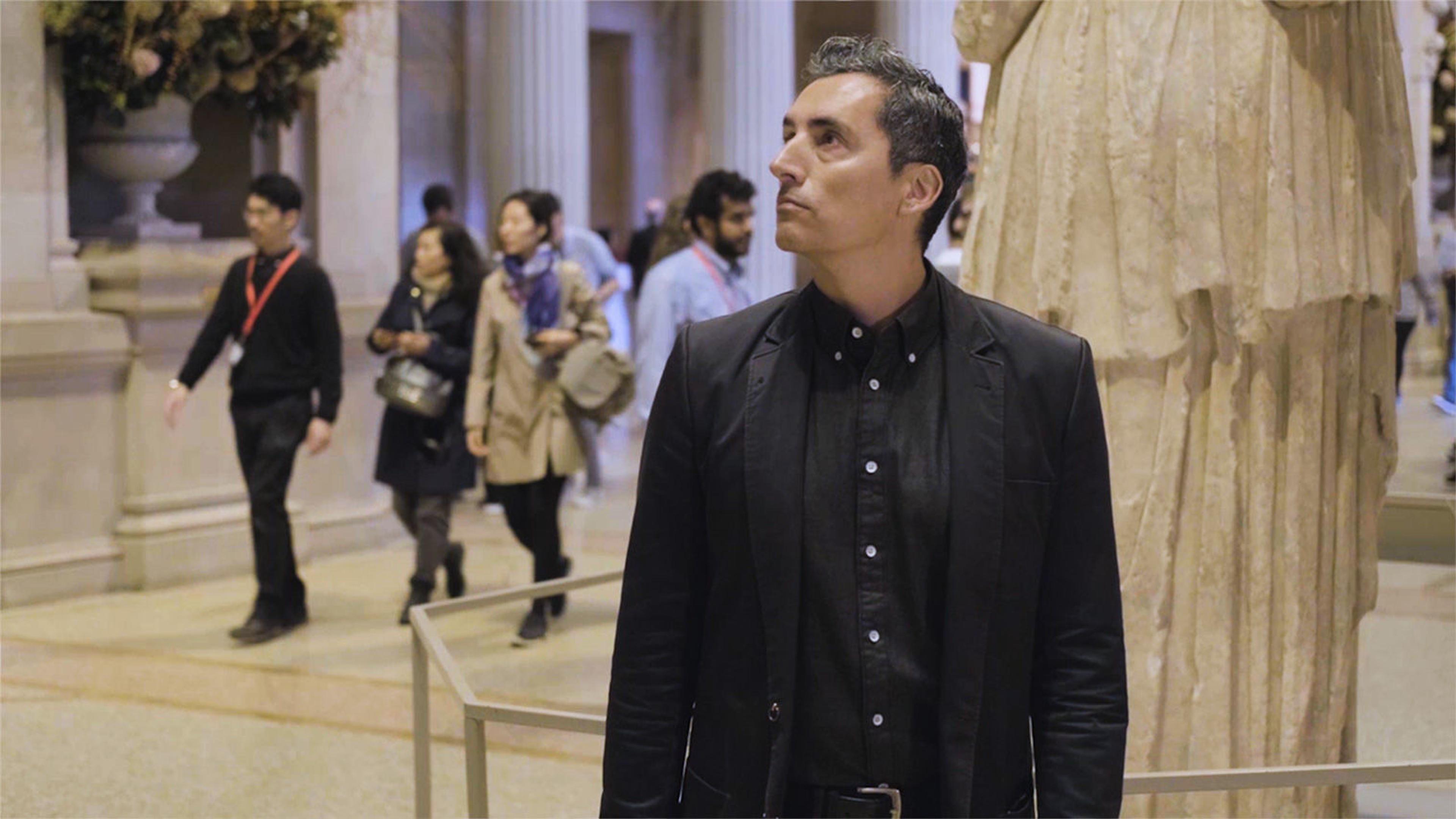 A artist Kent Monkman stands in The Met's Great Hall, looking around
