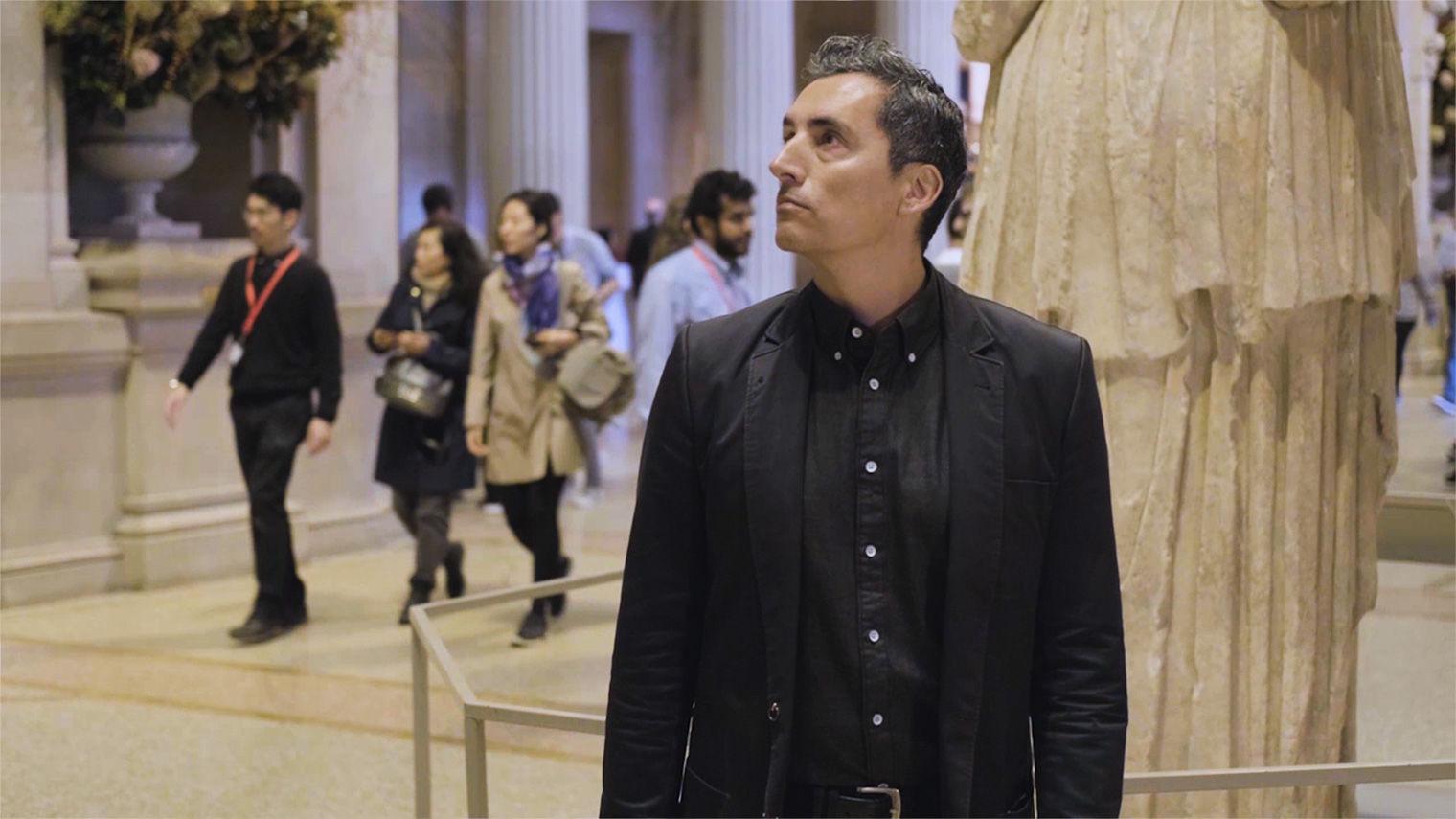 A artist Kent Monkman stands in The Met's Great Hall, looking around