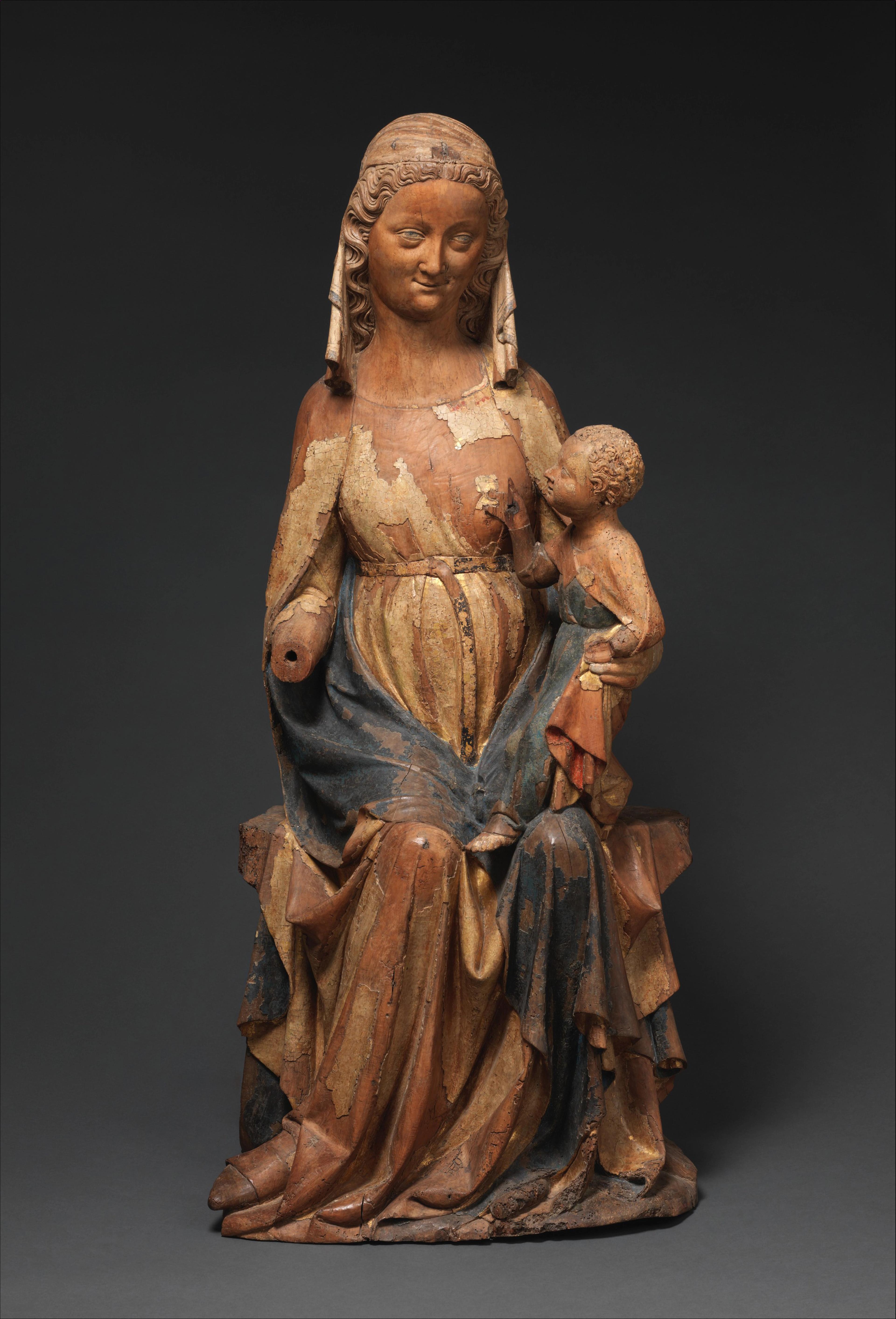 Paint-chipped statue of Mary with elegantly folded robes, holding a baby Christ in her left arm.