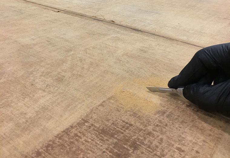 Conservation treatment showing the scraping away of lining adhesive on a painting's canvas