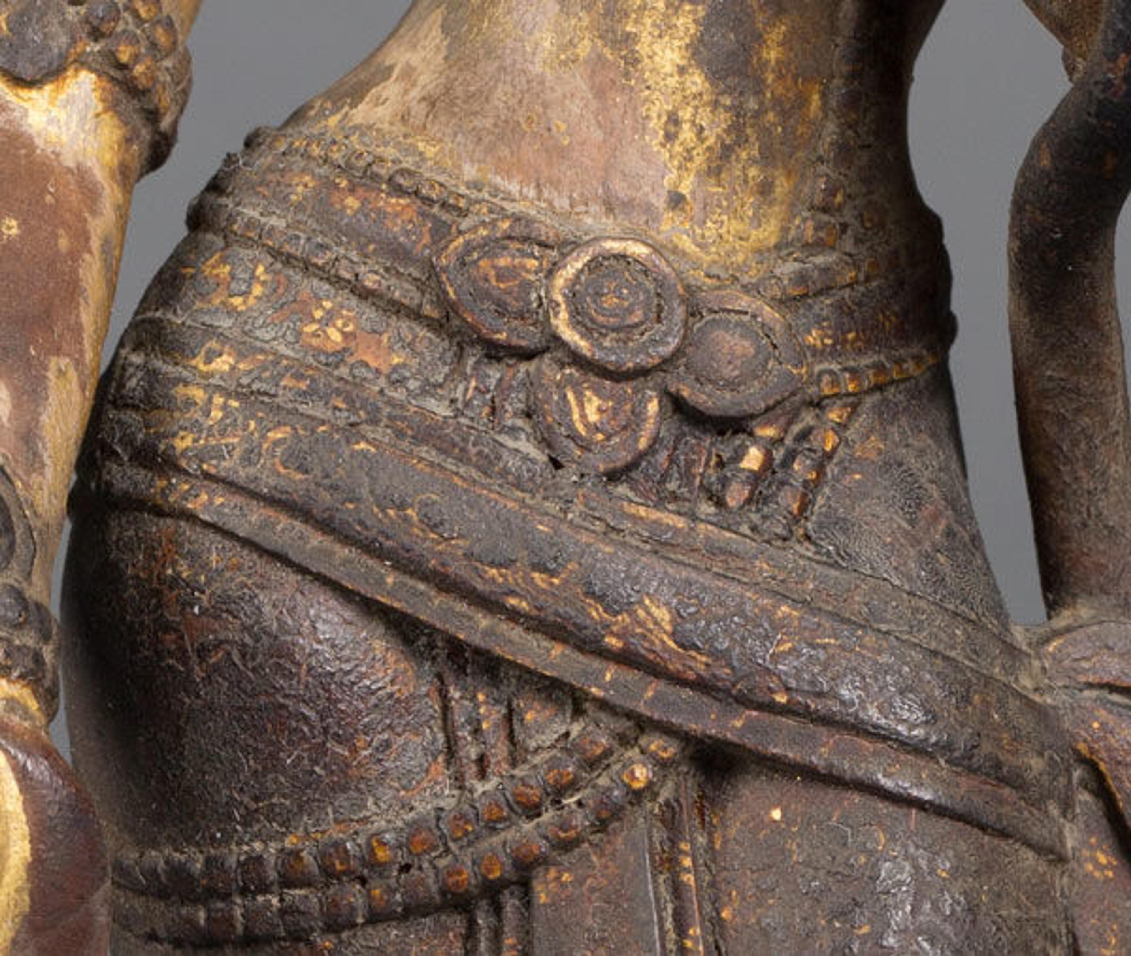 Detail of garment showing the degraded varnish (brown opaque crust) concealing the fine gilded details