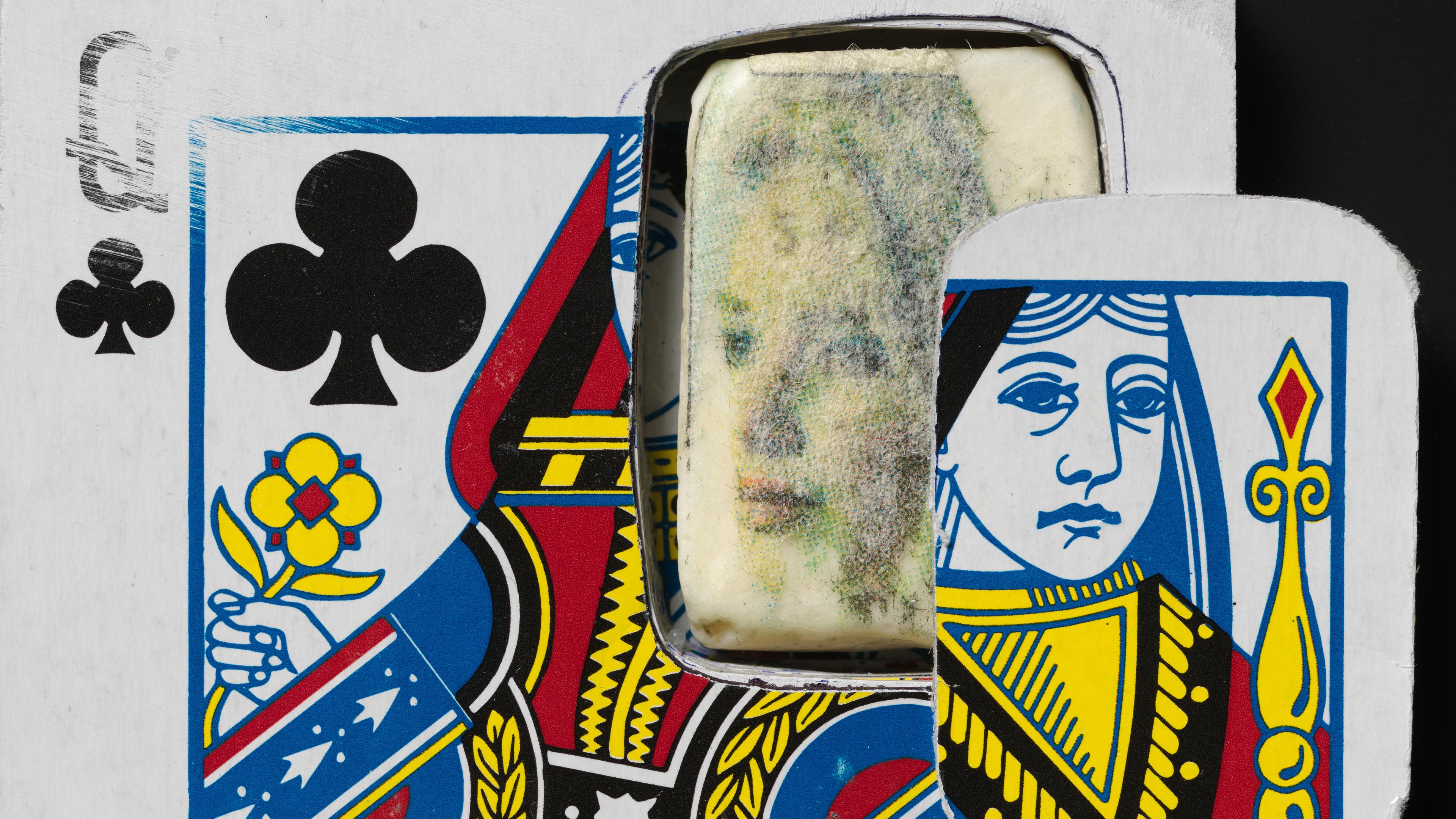 A Queen of Clubs playing card has a rectangular cutout revealing a faded passport photo underneath. Another card piece is partially overlaying her face.