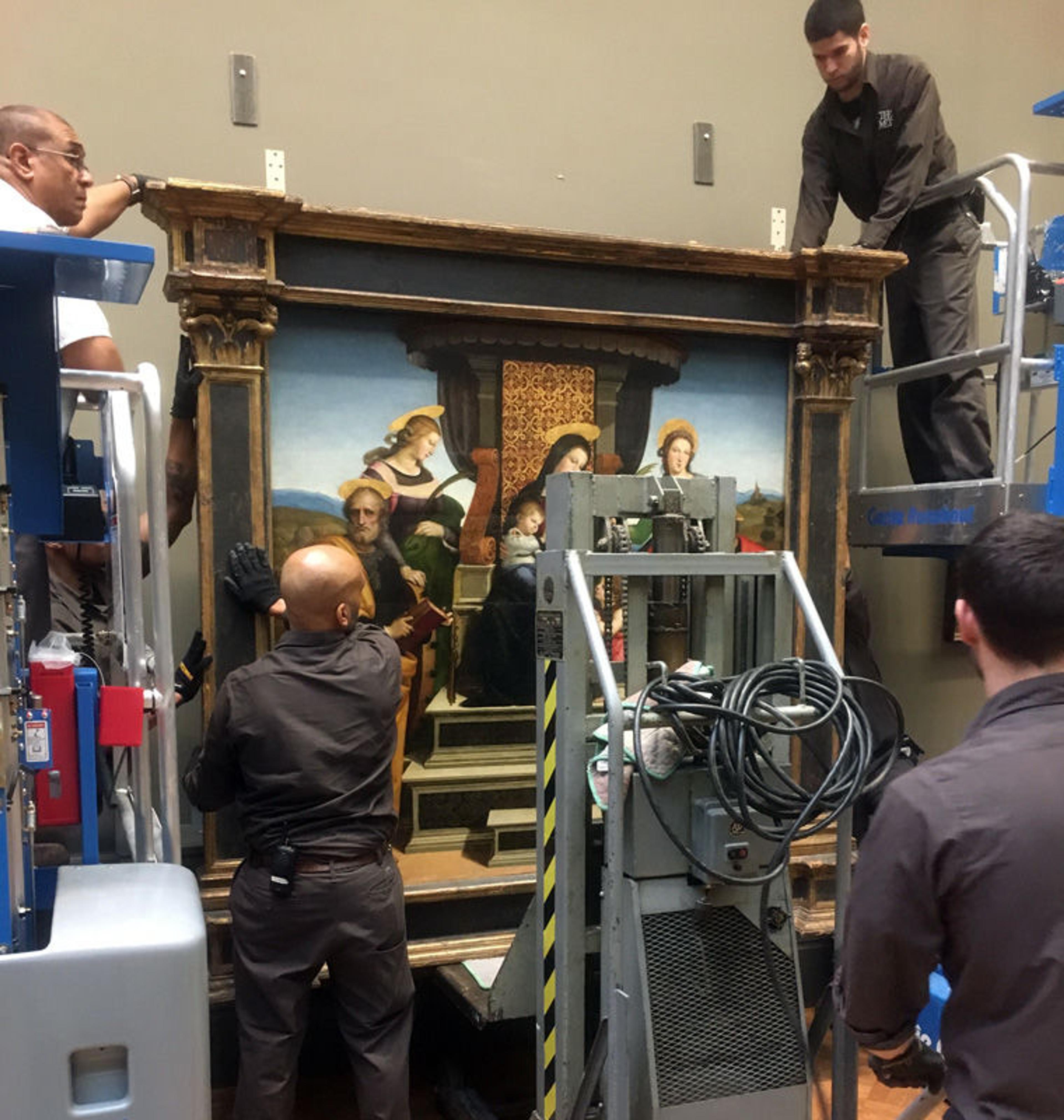 Museum staff secure an altarpiece by Raphael onto a rig