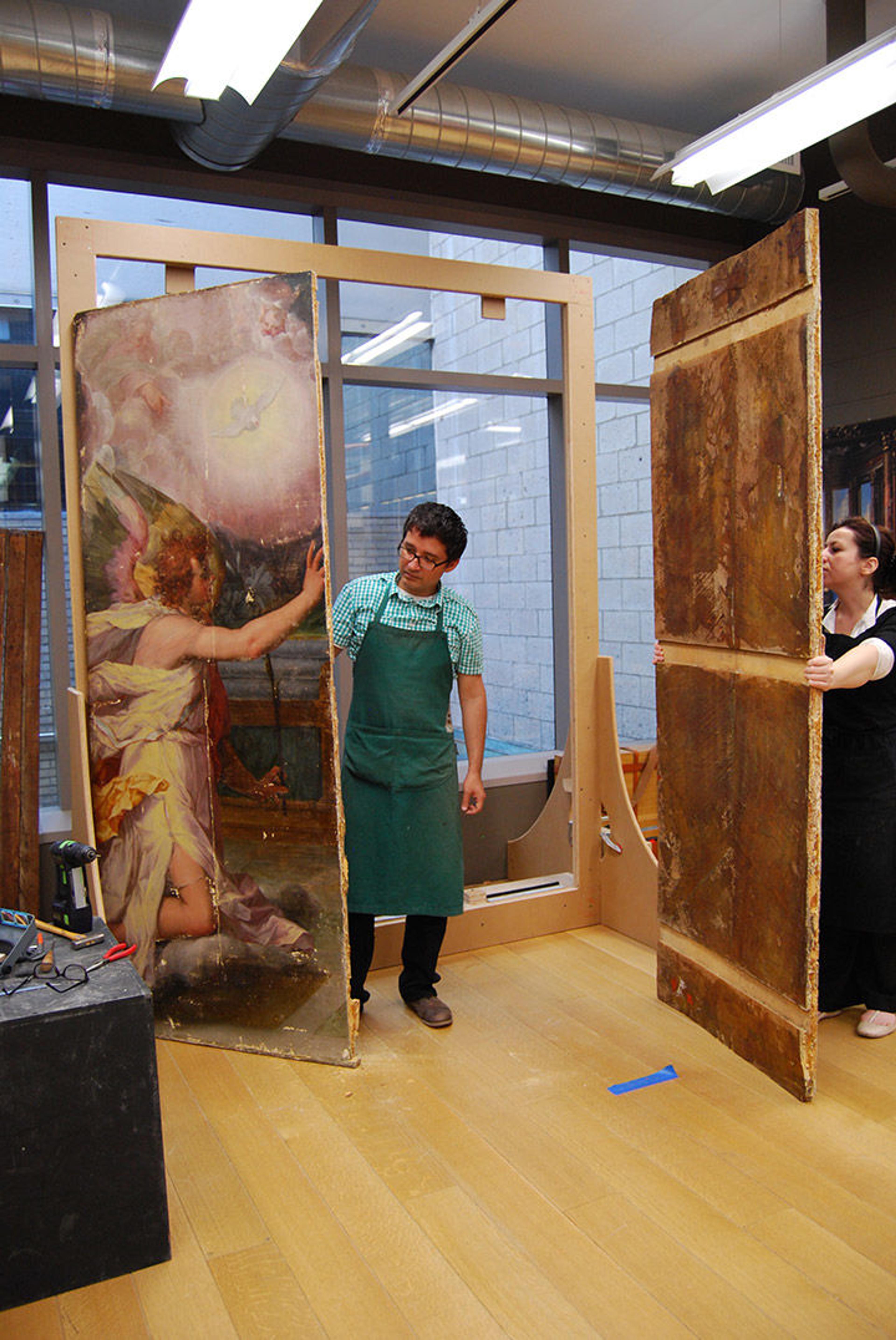Conservators each holding the two halves of the panel