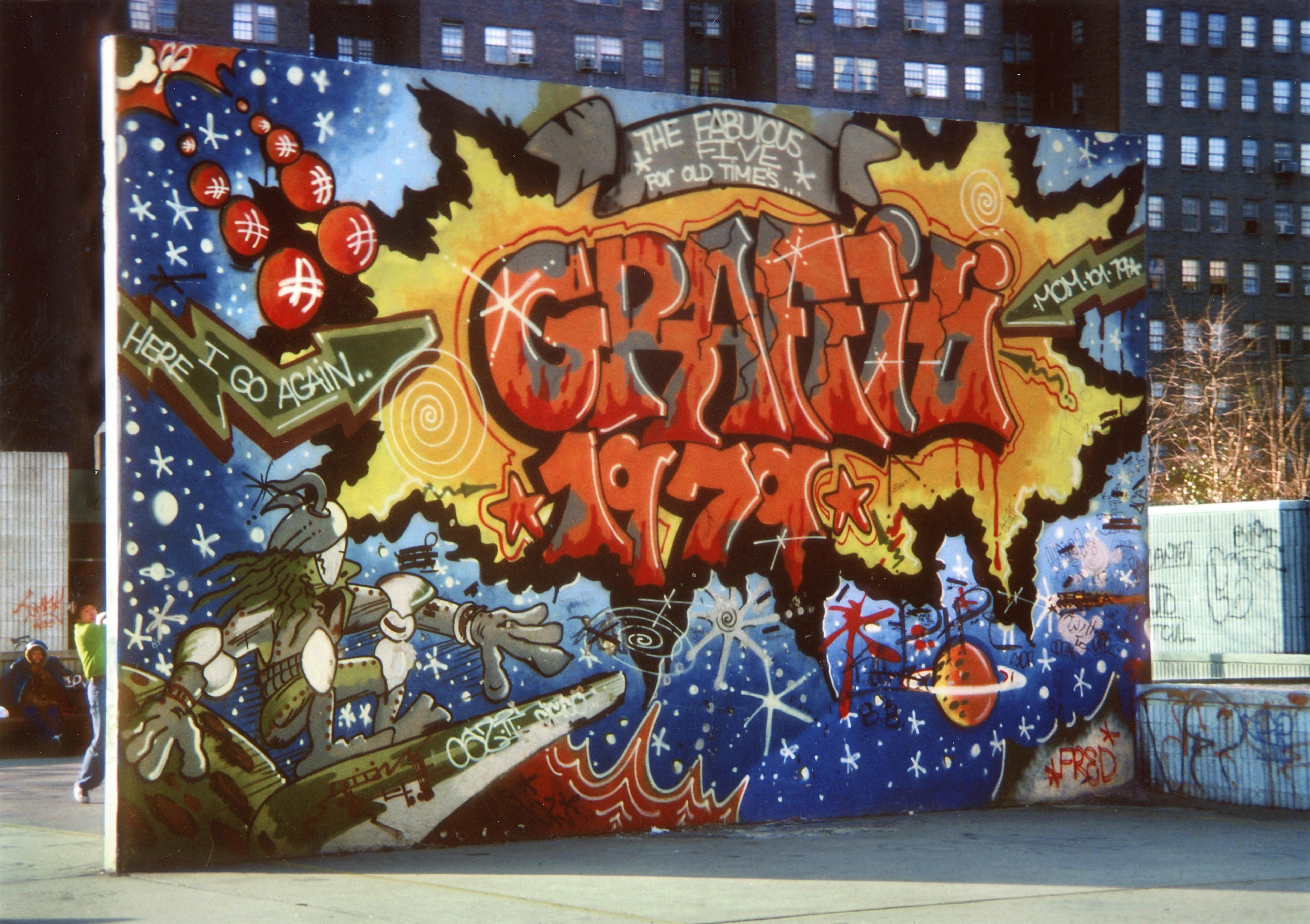 Graffitied wall on a handball court with an outer space scene.