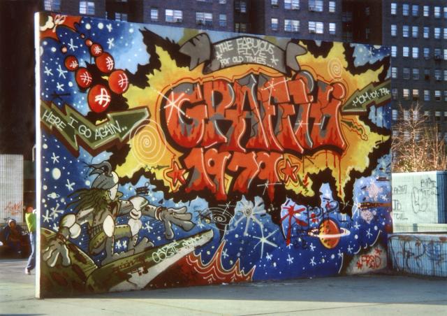 Graffitied wall on a handball court with an outer space scene.