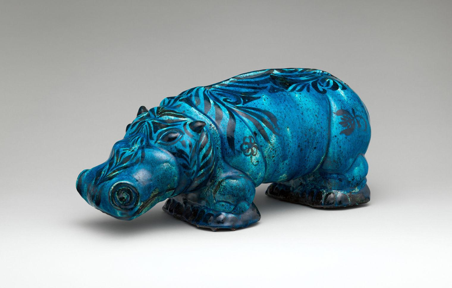 A small dark blue hippopotamus with detailed facial features and dark floral patterns painted on the head and body.