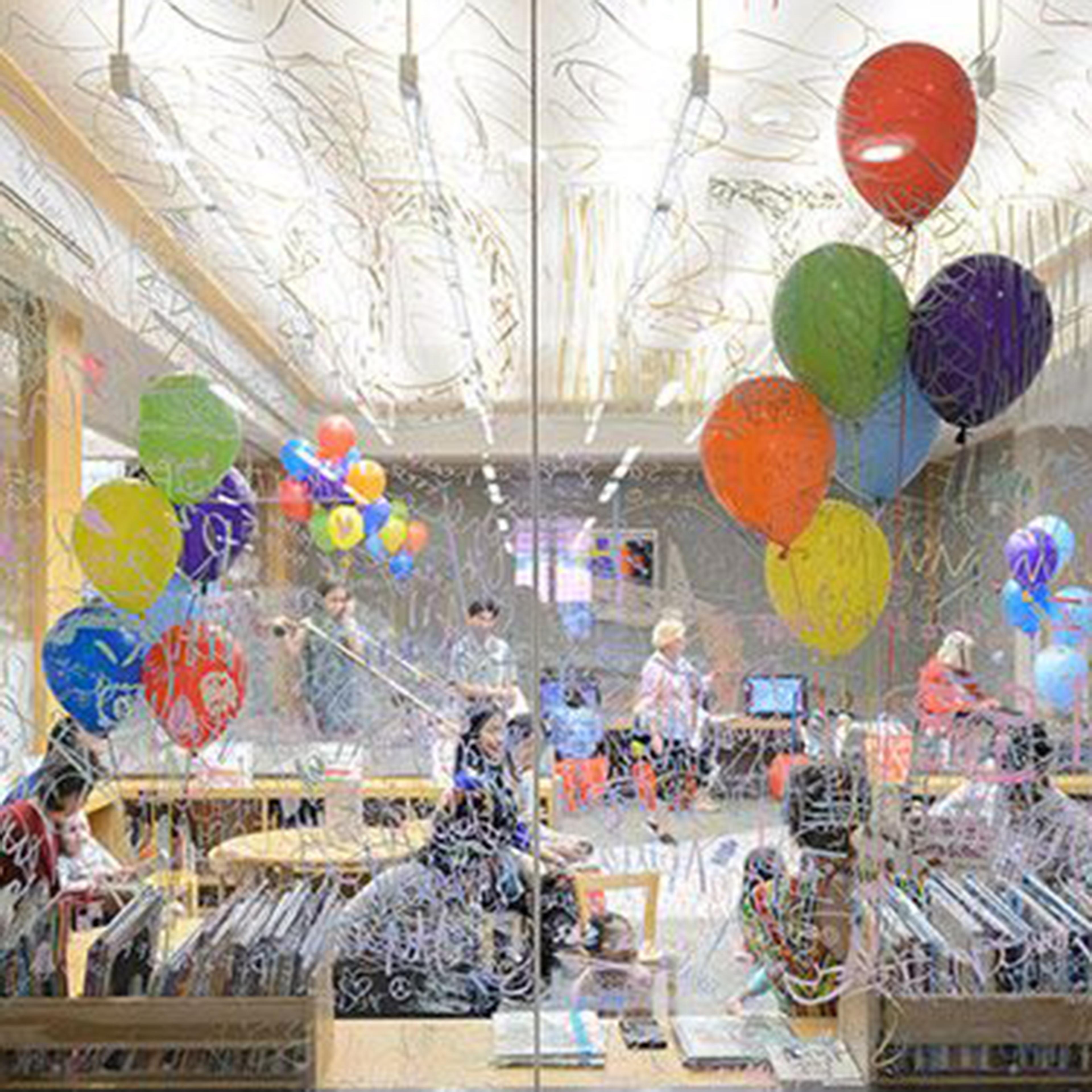 Balloon-filled room with parents and kids, seen through a window.