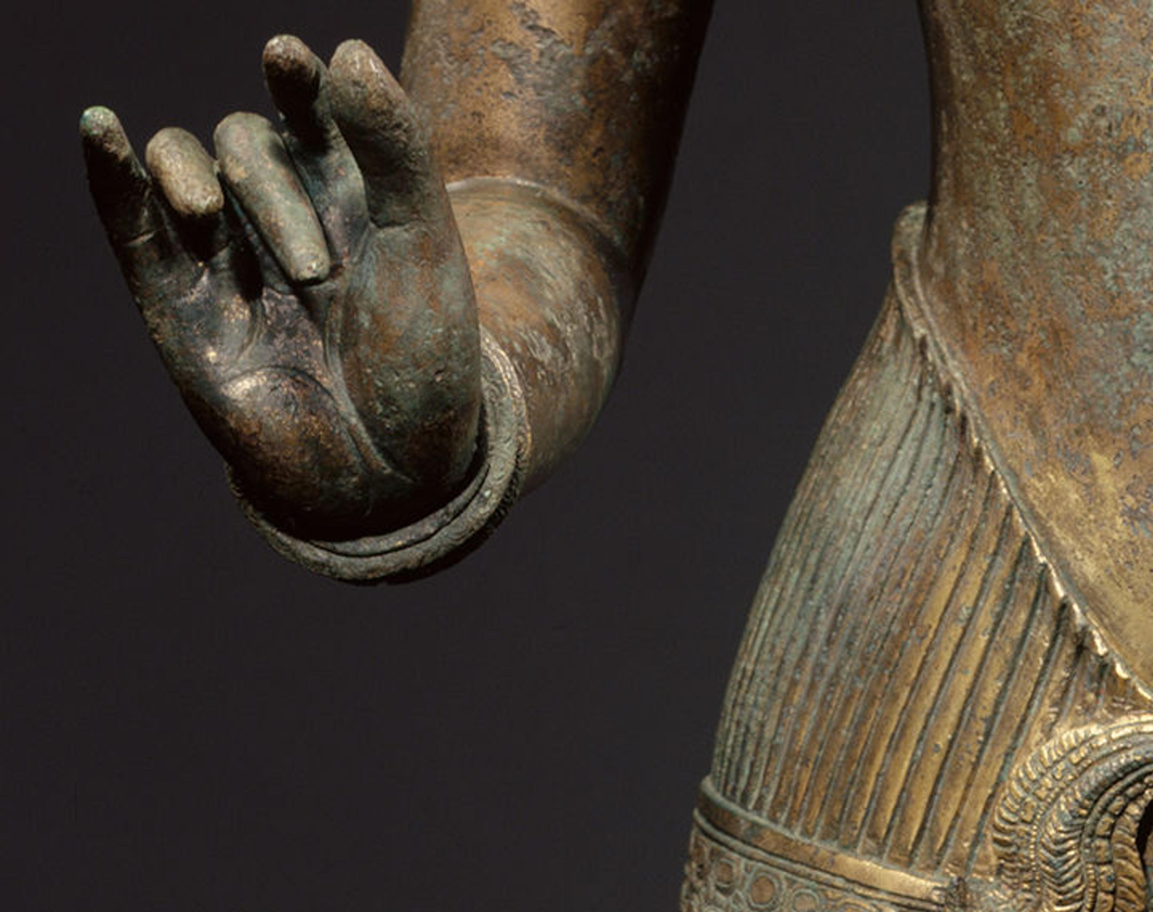Detail of a sculpture of a standing deity, probably Shiva. The hand is turned upwards with poised fingers.