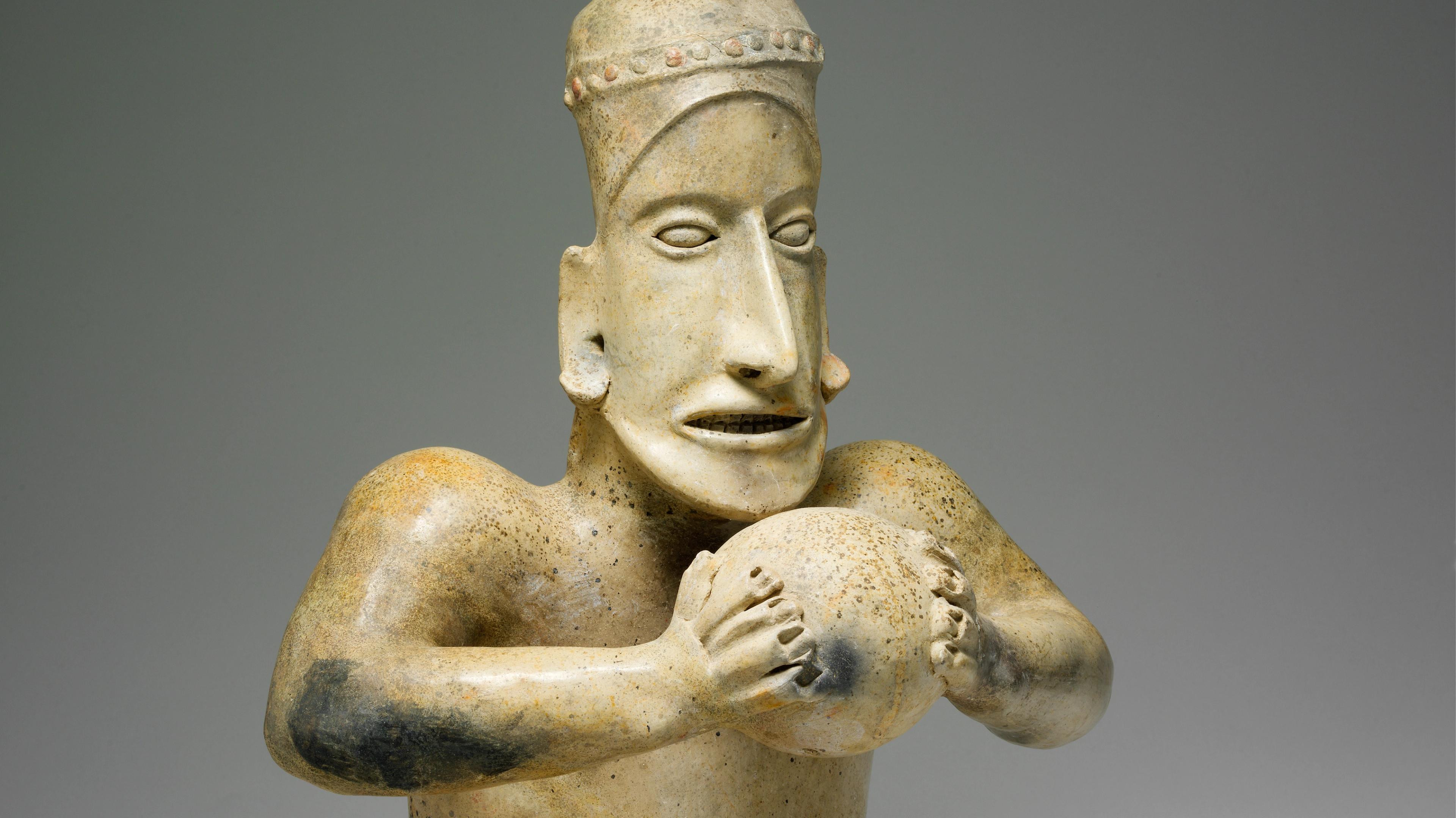 Ceramic seated ballplayer figure holding a ball