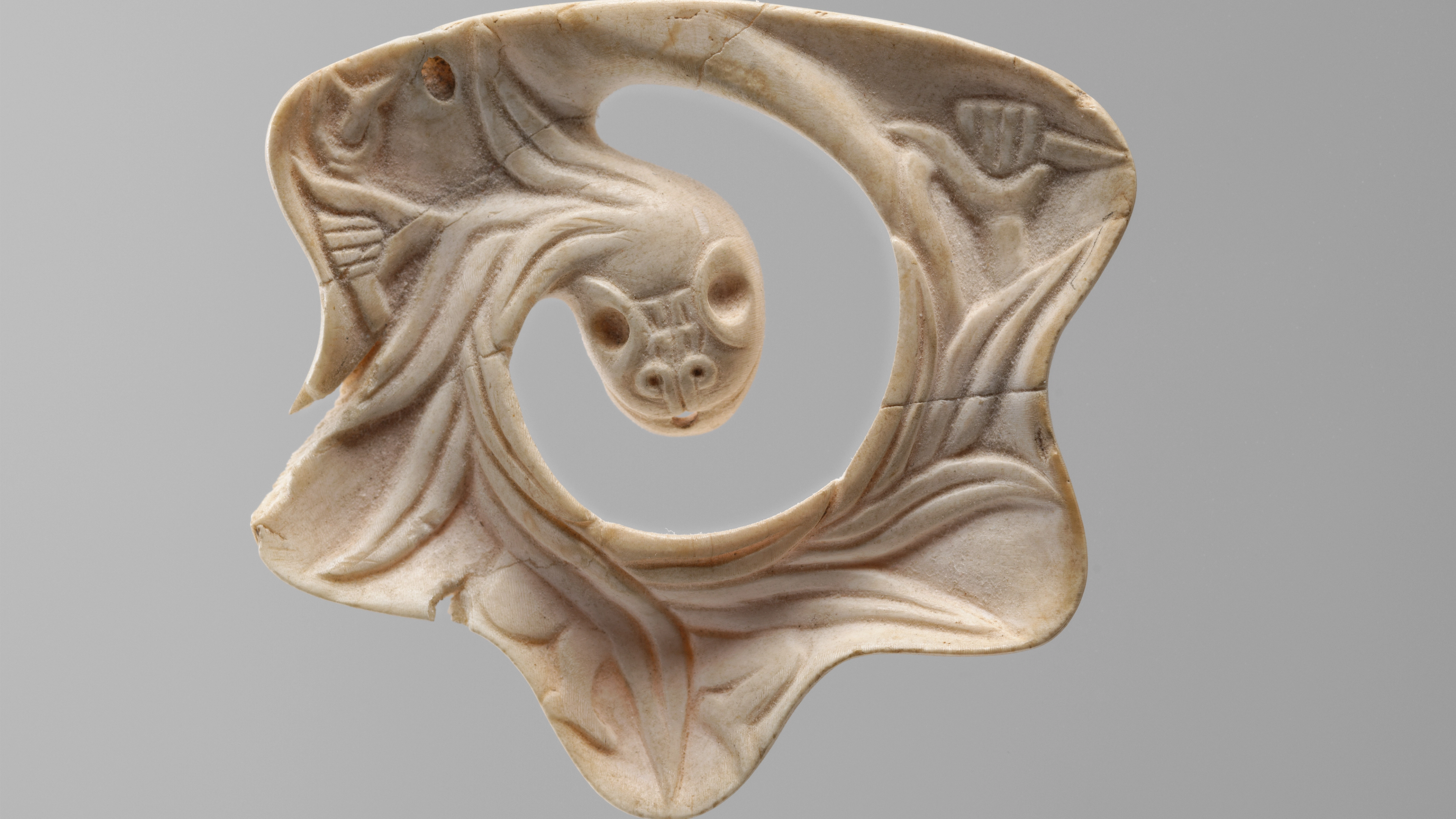 Carved feathered serpent pendant made from conch shell