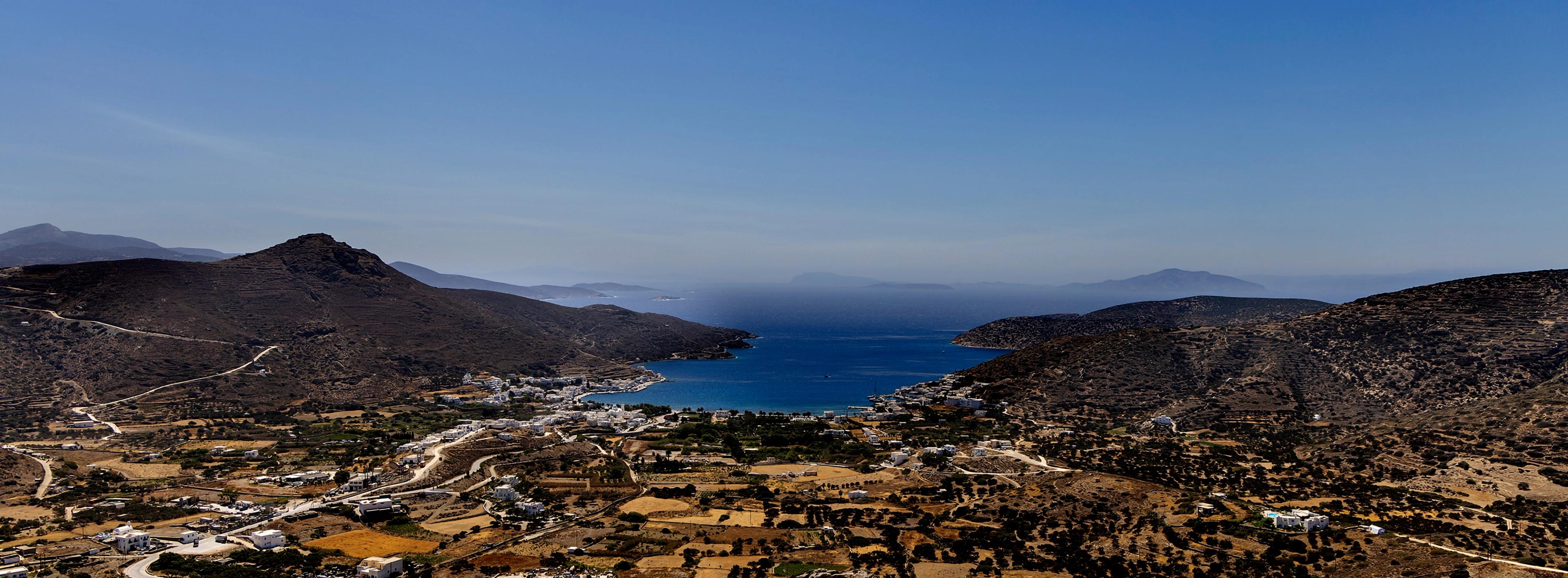 Picturesque landscape of mountains and valley surrounding three sides of a deep blue sea.