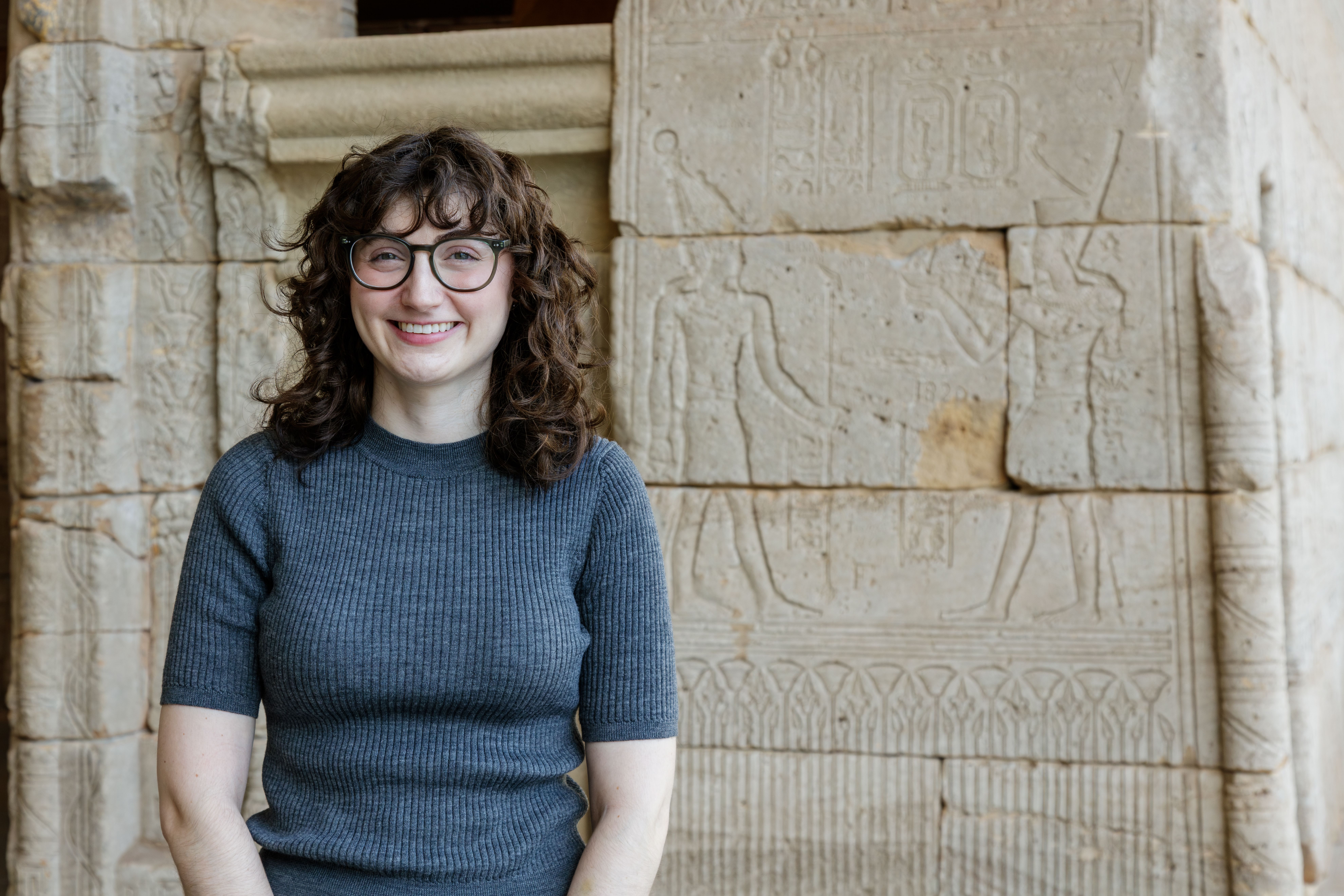 Elana stands in front of the Temple of Dendur. She has on a gray sweater.