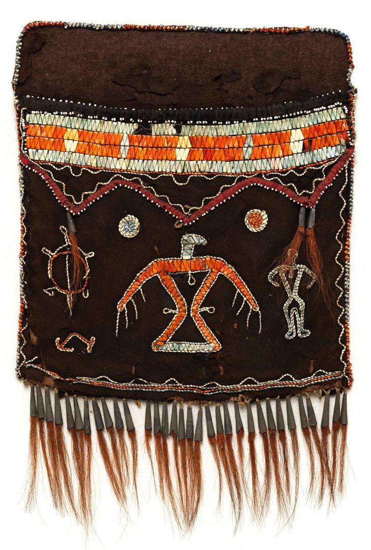 A brown deer hide shoulder bag with orange, blue, yellow, and white porcupine embroidery of different spirits and animals and a deer hair fringe at the bottom. There is no strap.