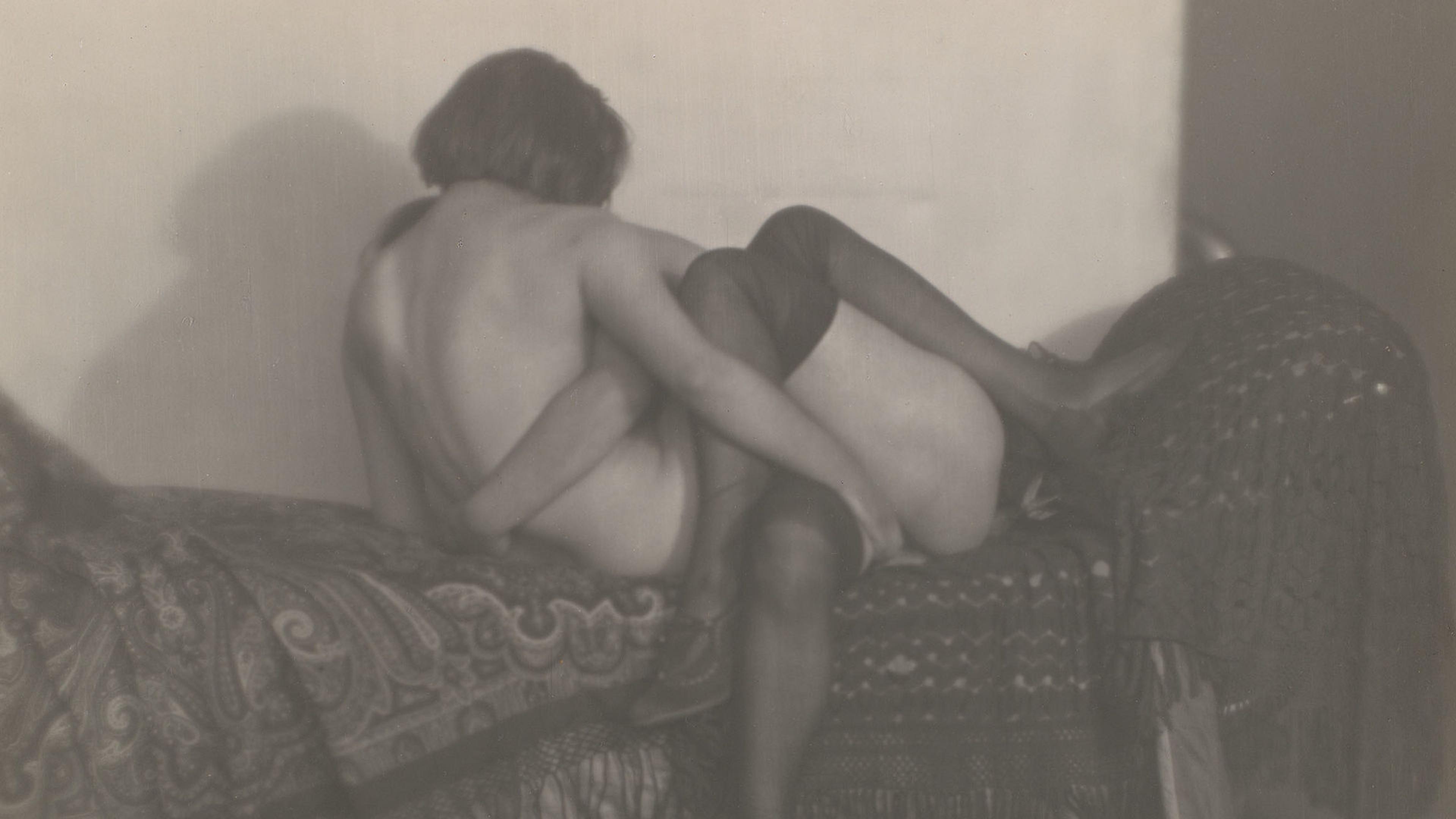 A black and white photograph of two nude women in a loving embrace.