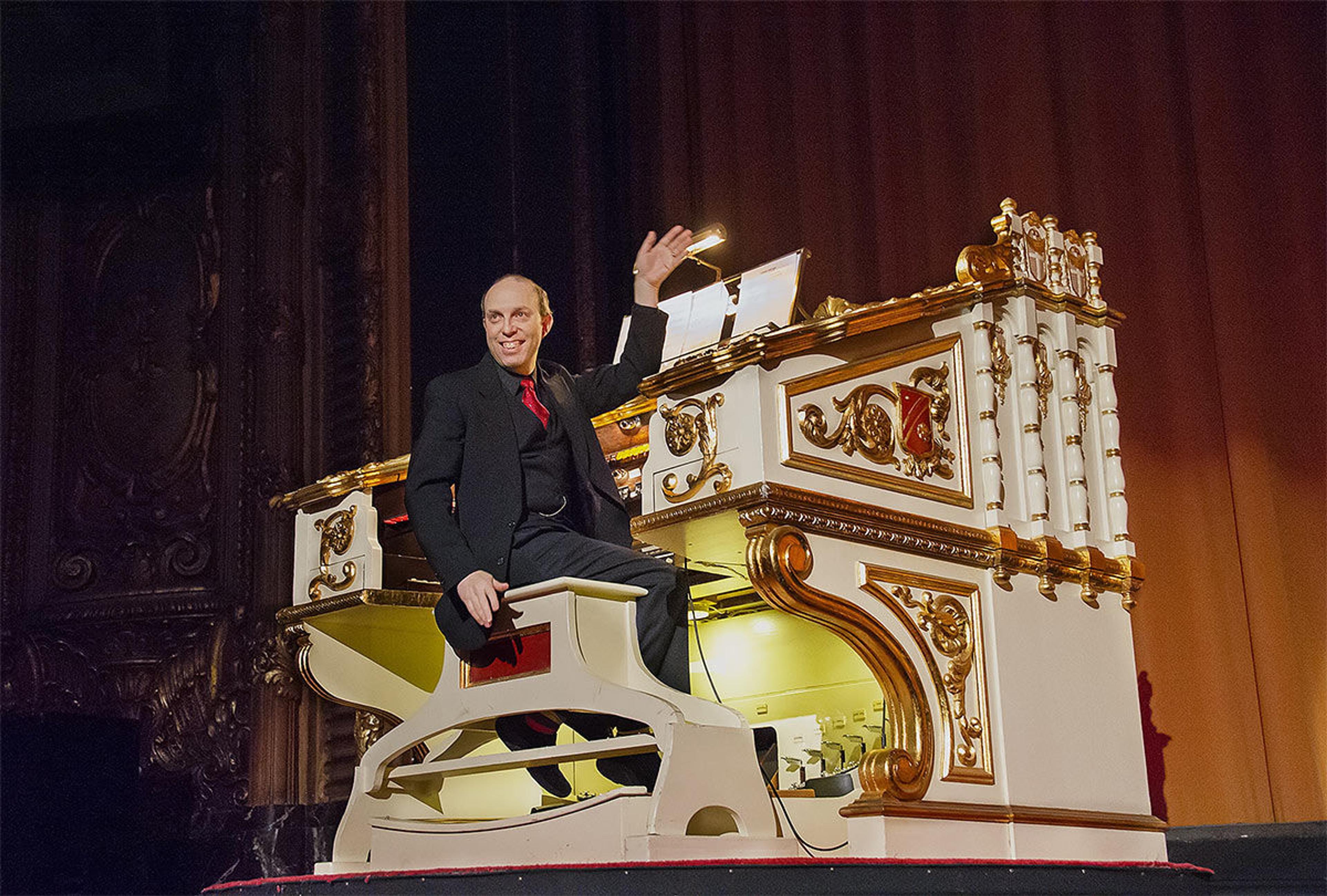 A photograph of the pianist Ben Model waving on the stage of a grand theater