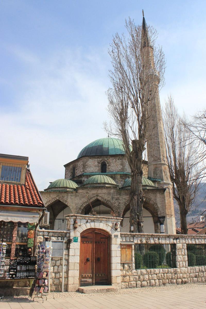 The Baščaršija Mosque and its stone gate, next to a souvenir stall in the old bazaar