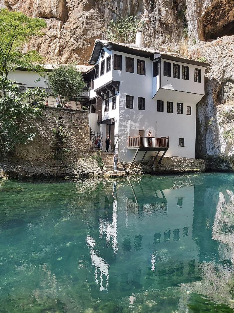 The white Blagaj Tekke under a cliff, reflected in the clear blue-green Buna spring