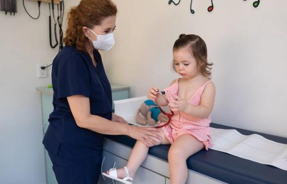 A child is examined by a nurse in a pediatrician's office, emphasizing gentle healthcare.