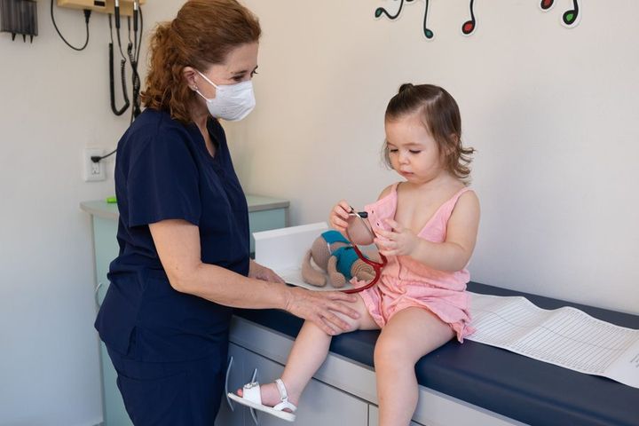 A child is examined by a nurse in a pediatrician's office, emphasizing gentle healthcare.