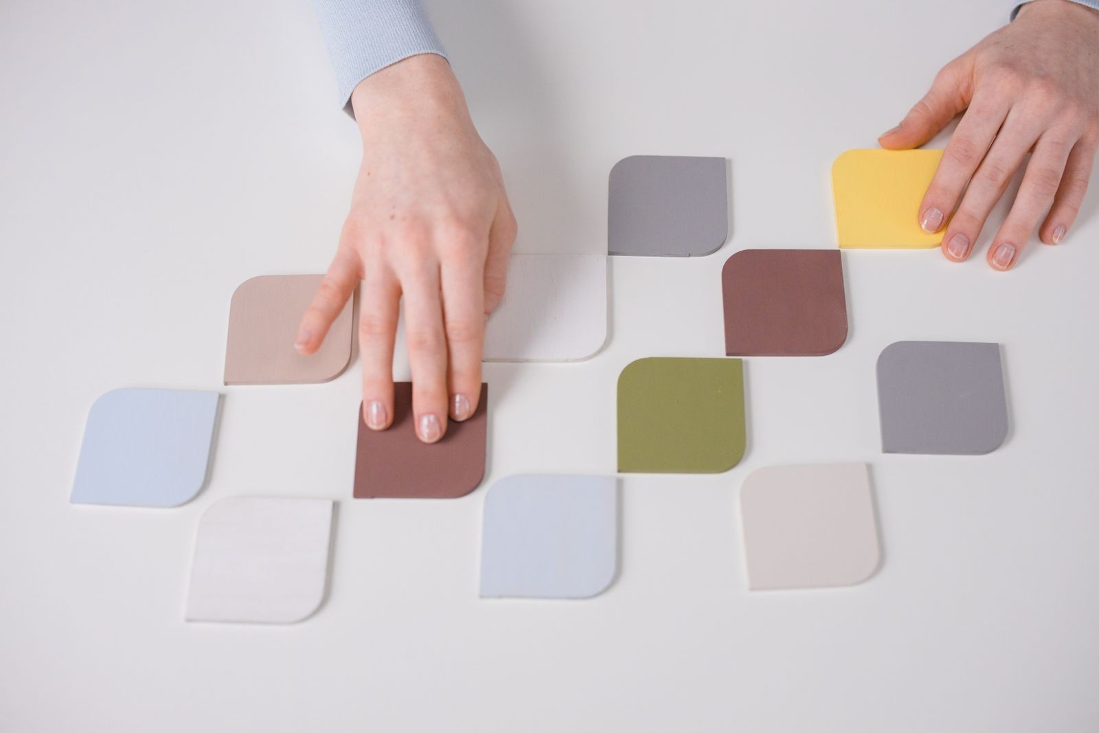 Hands arranging colorful brand color swatches on a white table