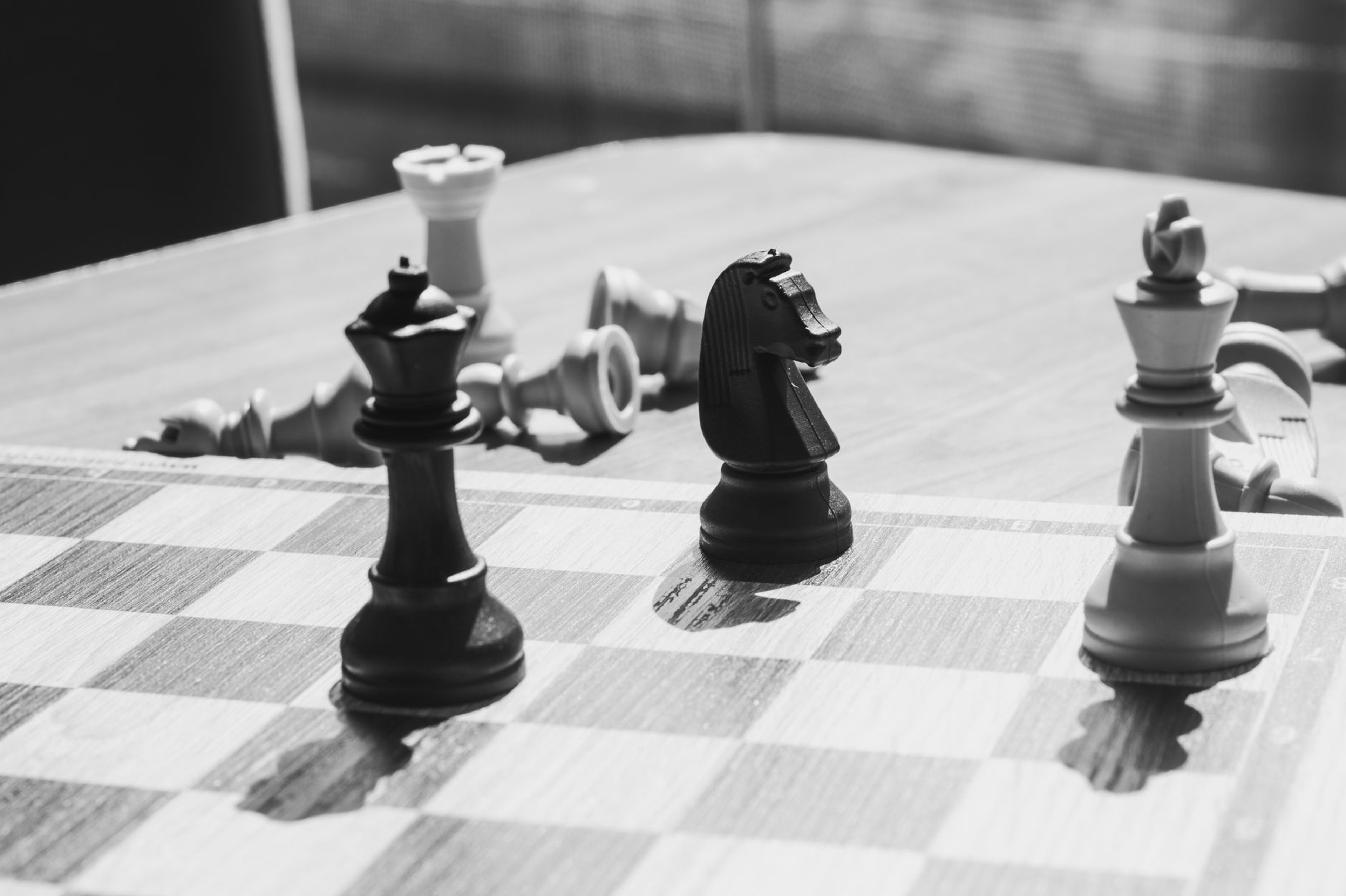 Black and white chess pieces standing upright next to others fallen on the board