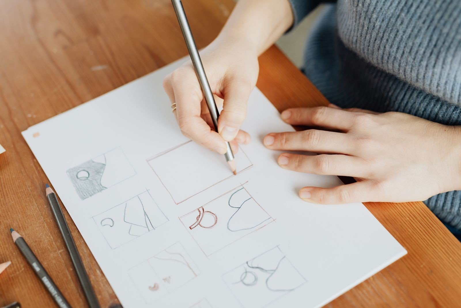 Overhead view of a designer's hands sketching logo concepts on paper