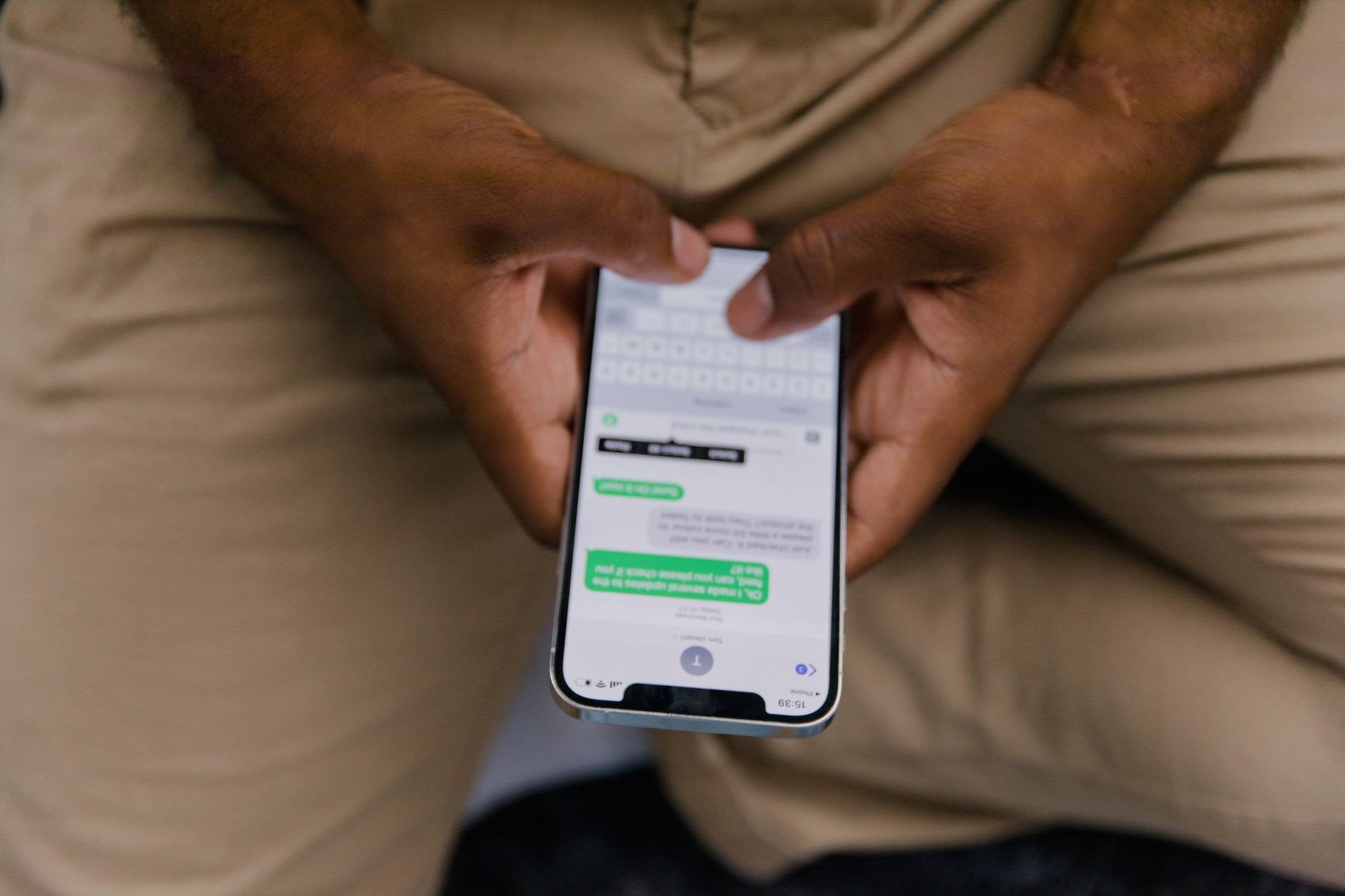 Close-up of two hands holding a smartphone open on a chat conversation