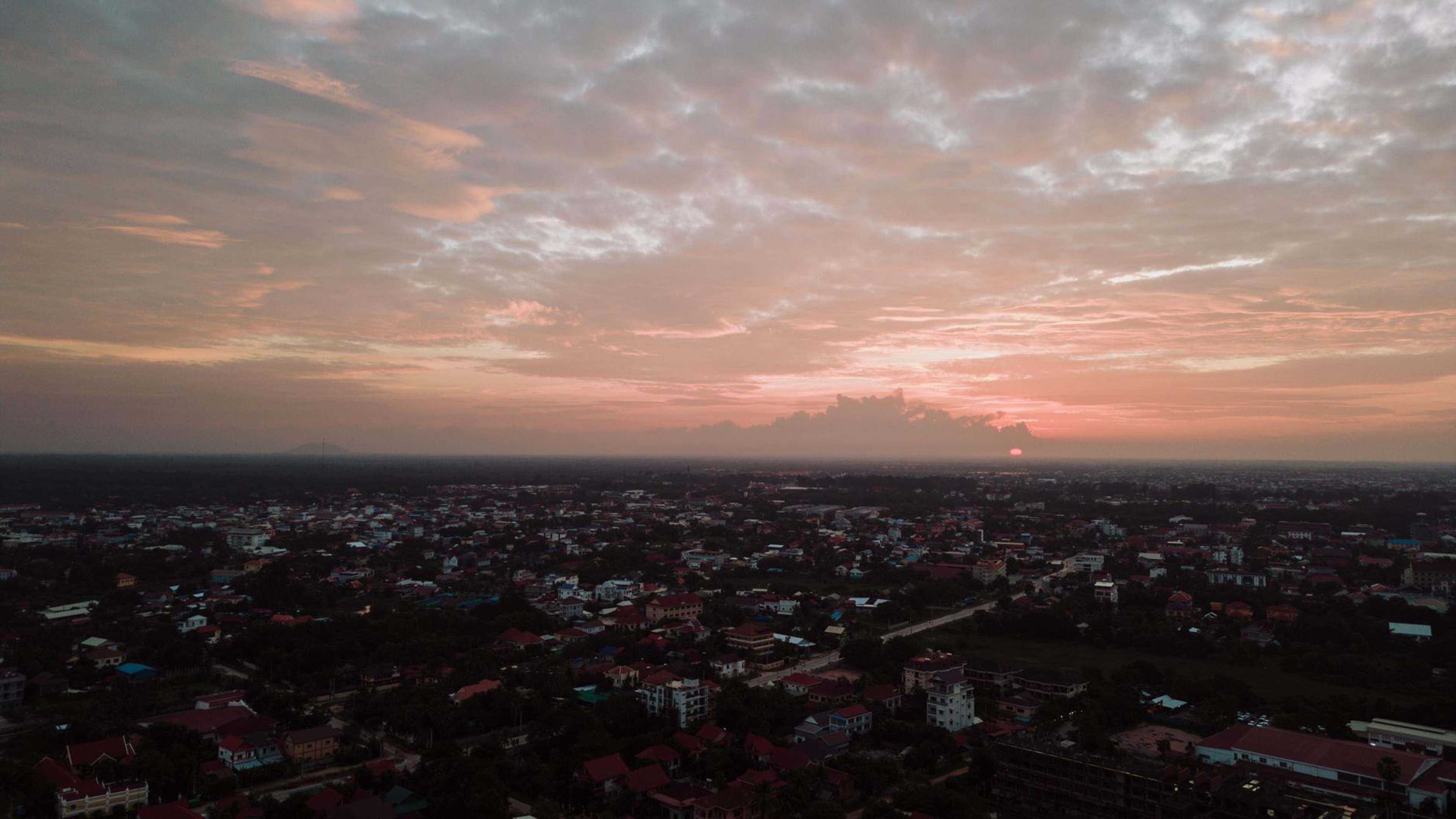 Aerial view of Krong Siem Reap at sunset, rooftops of the city stretching toward the horizon