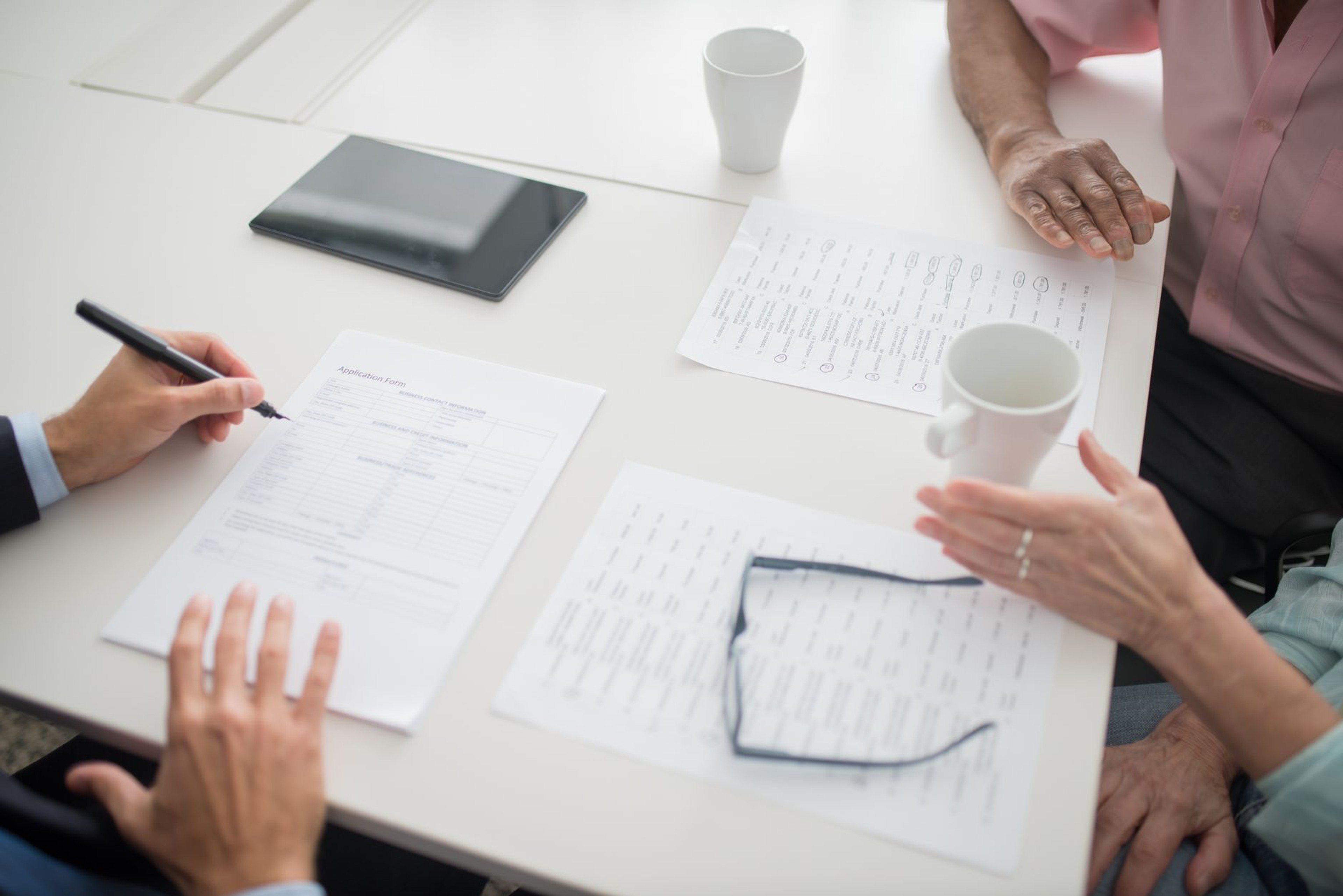 Business team reviewing proposal documents and a tablet together