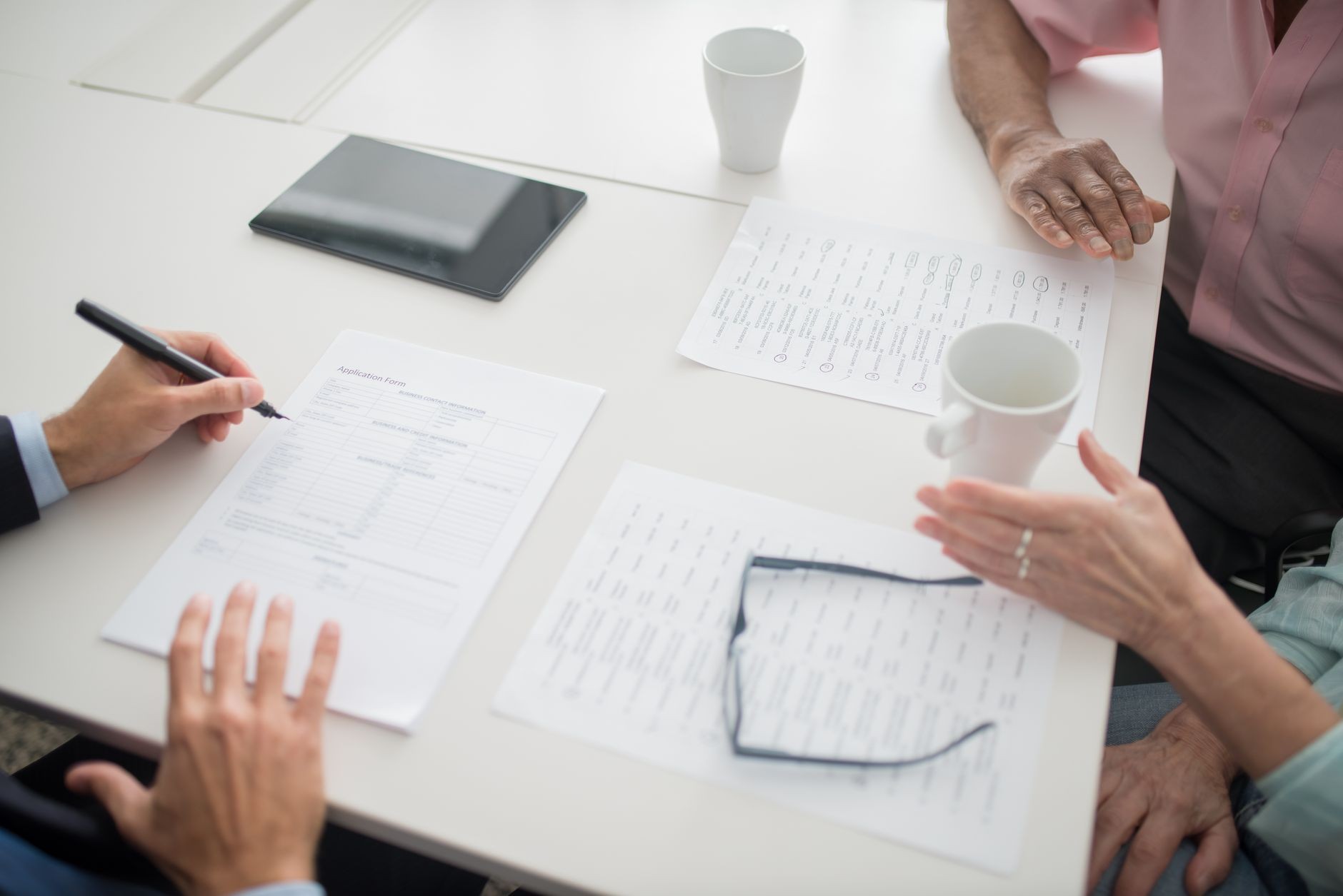 Business team reviewing proposal documents and a tablet together