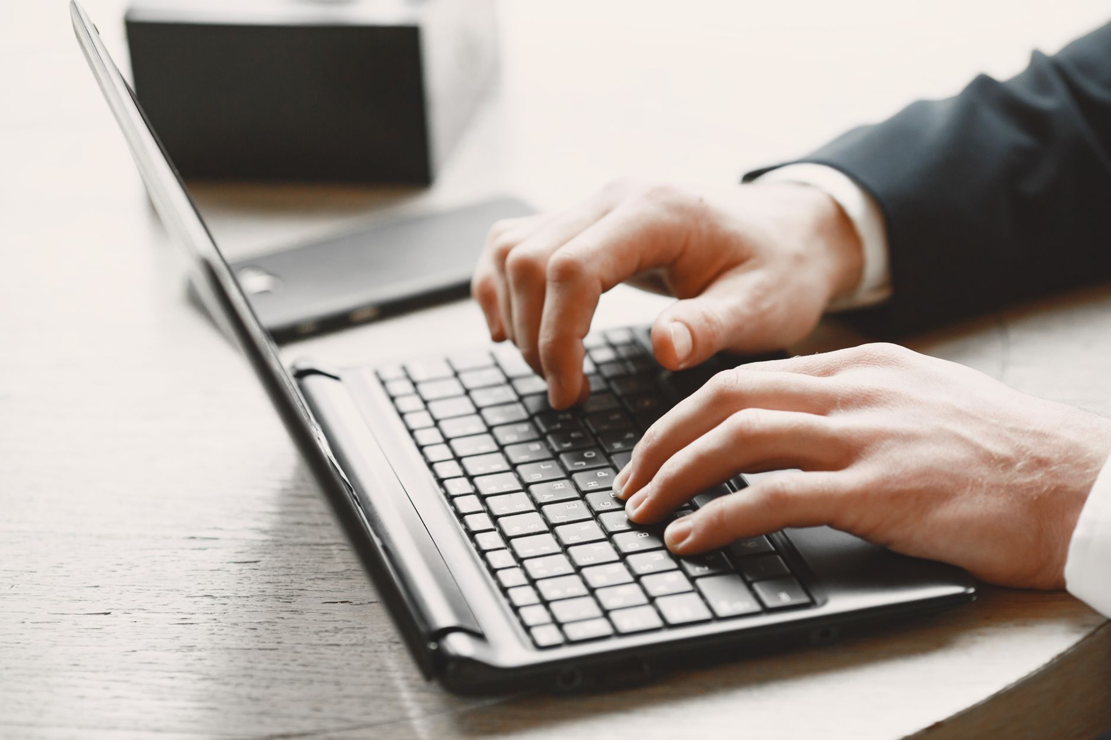 Close-up of hands typing on a laptop keyboard in a professional office setting