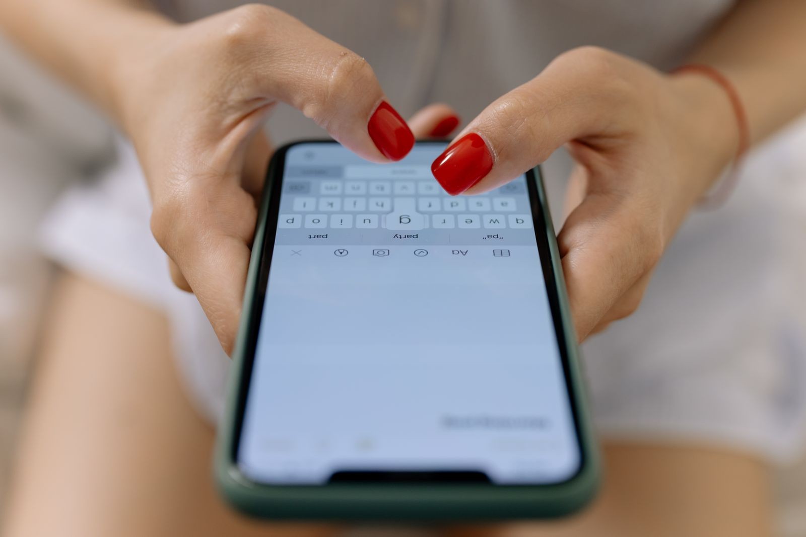 Close-up of two hands typing a message on a smartphone