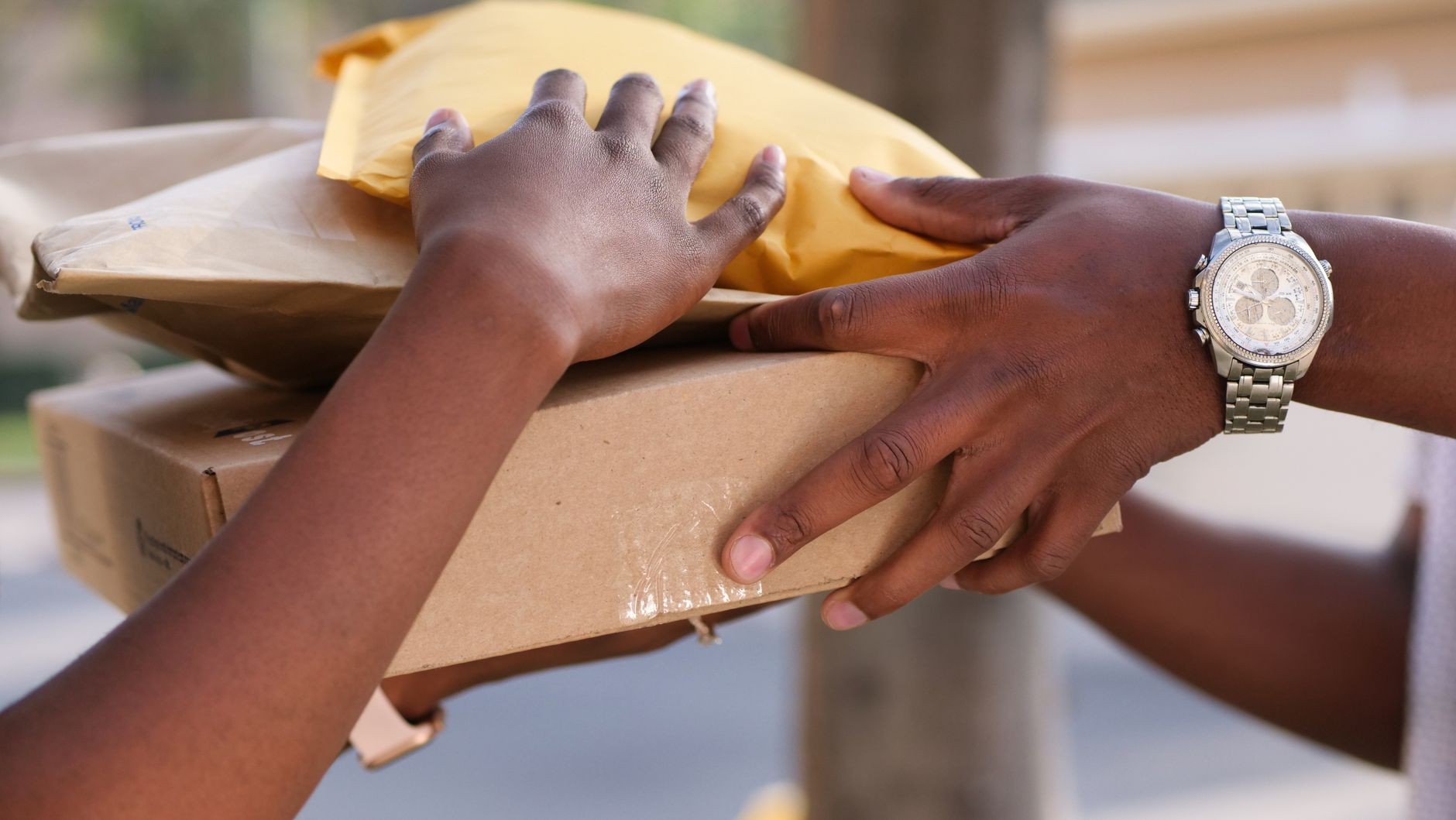 Hands exchanging a parcel during a home delivery