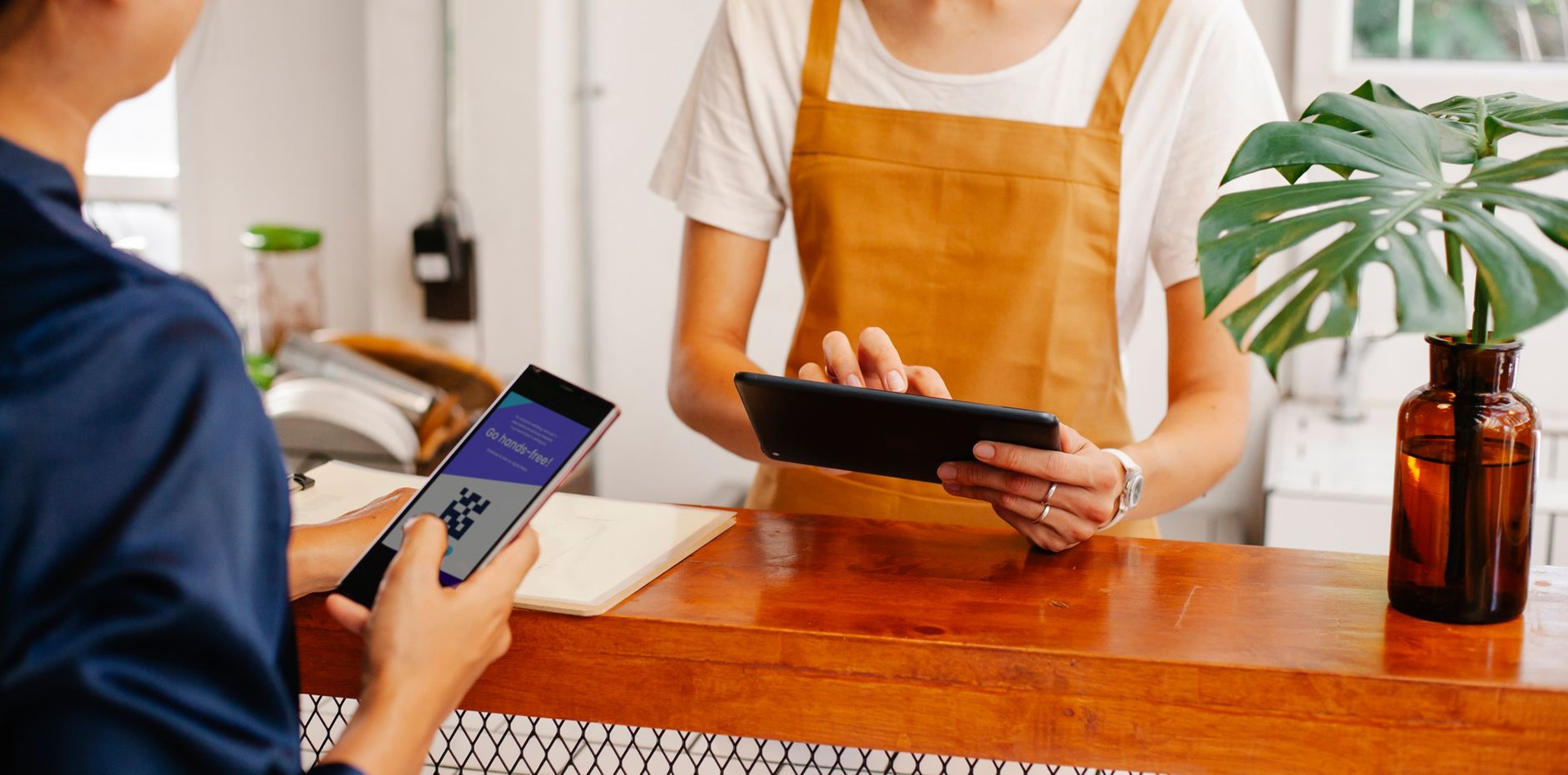 Cafe worker and customer completing a QR code payment at a shop counter
